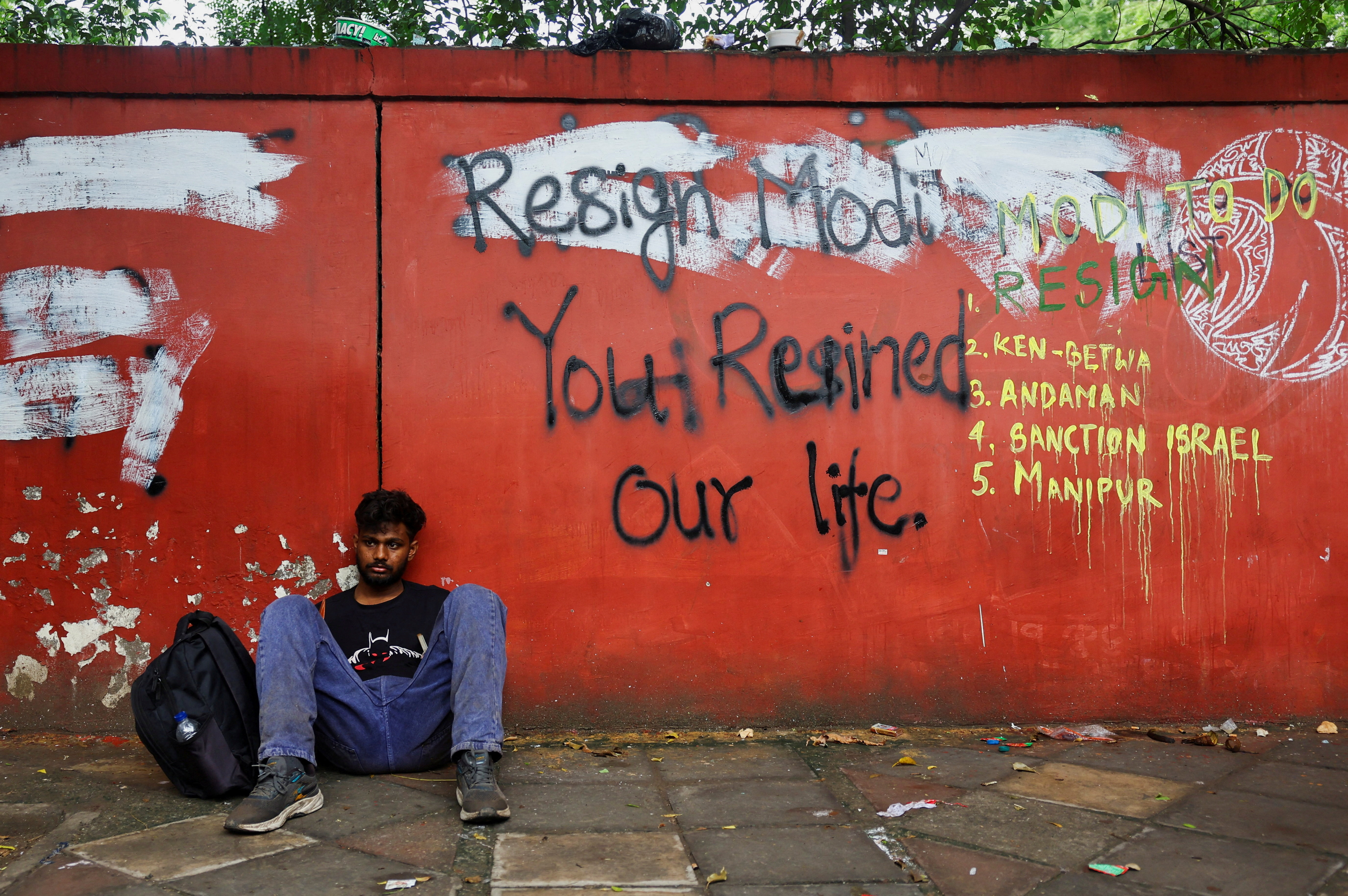 A supporter of India’s Cockroach Janta Party (CJP) sits on the ground as he rests during ongoing protests, two days after thousands of protesters marched towards parliament demanding the resignation of Education Minister Dharmendra Pradhan over examination paper leaks, at Jantar Mantar in New Delhi, India, on July 22, 2026