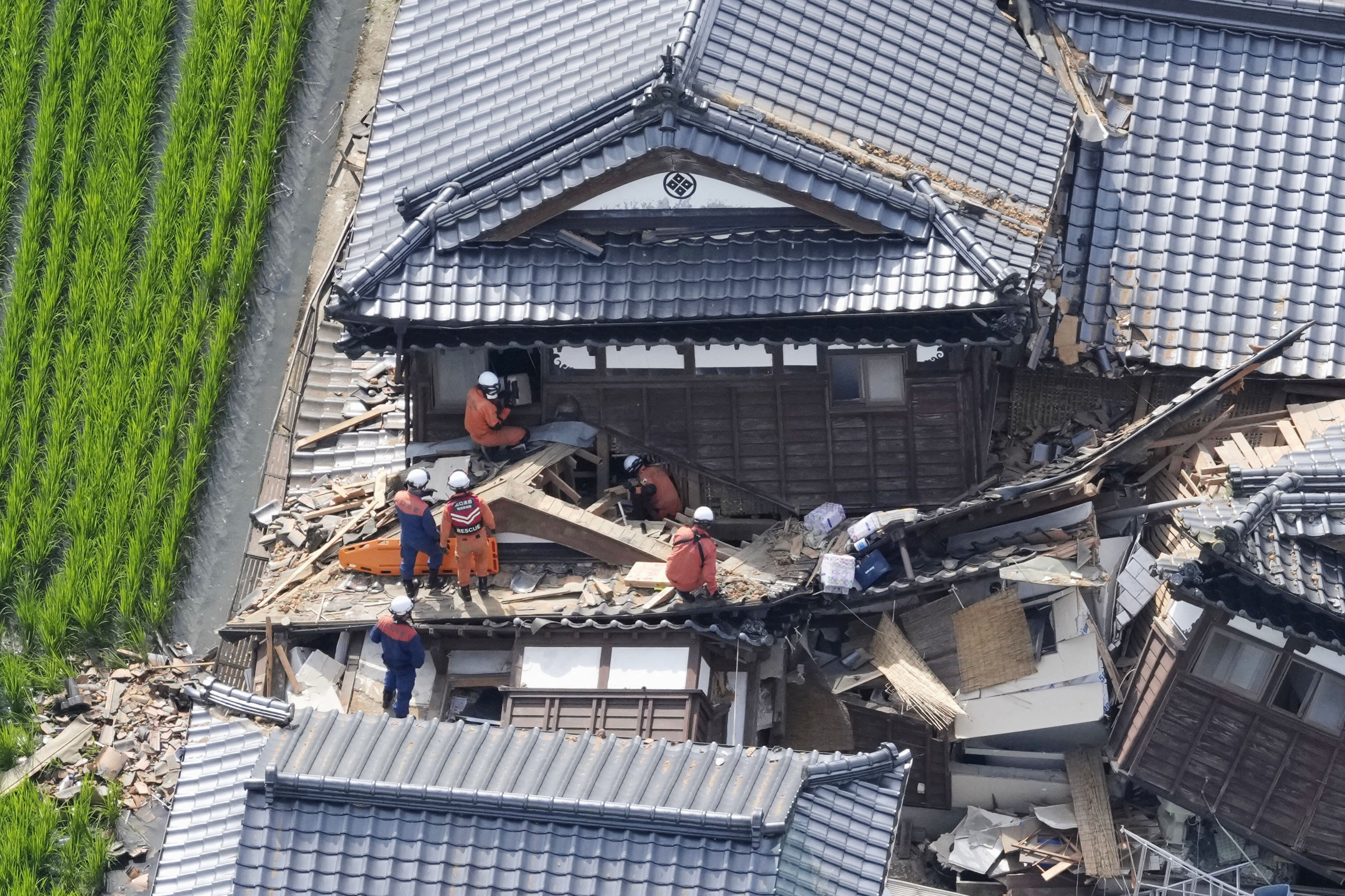 Emergency workers carry out search and rescue operations at a collapsed house after an earthquake with a magnitude of 7.1 struck Japan's southern Kumamoto prefecture