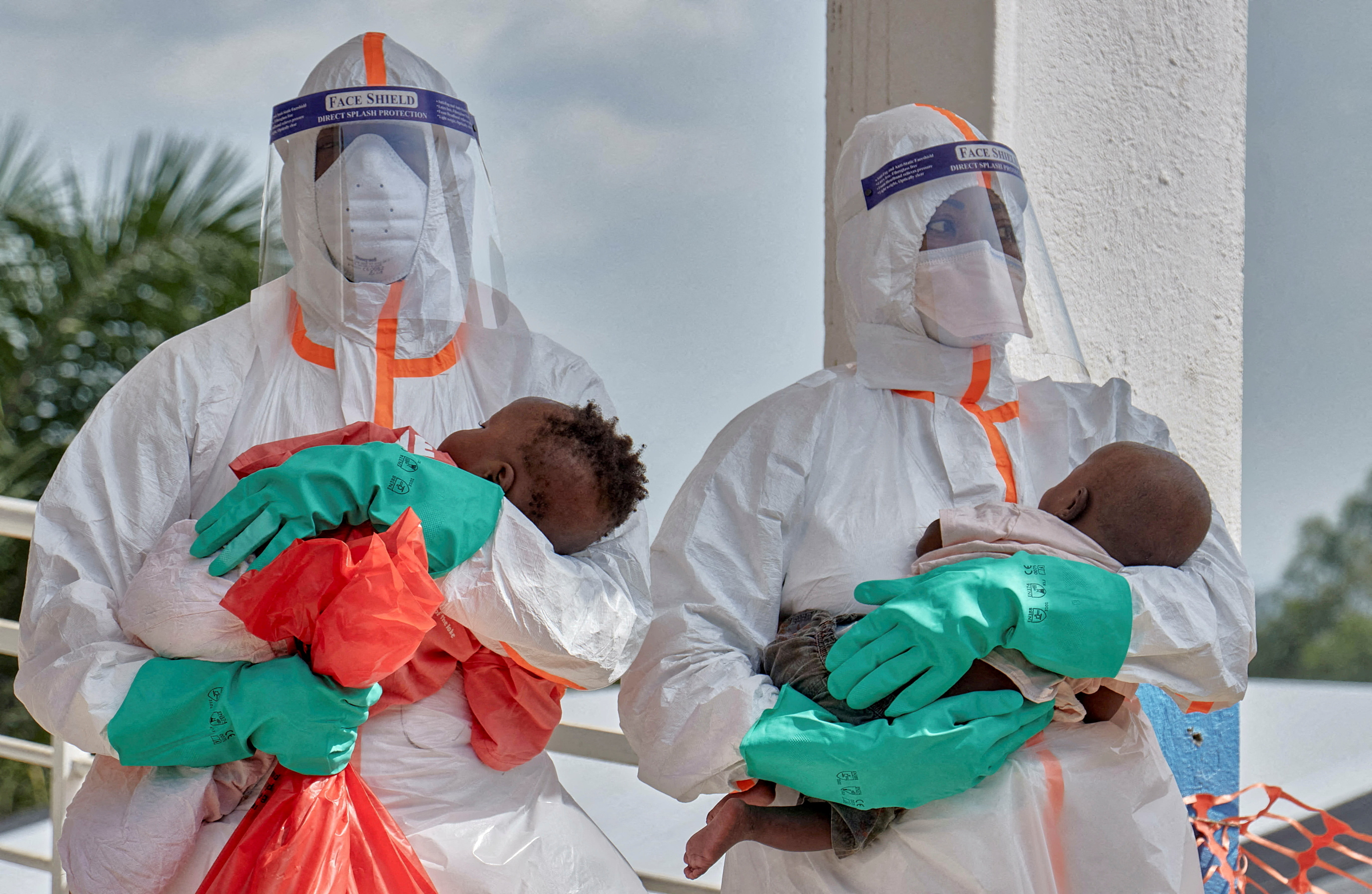 Congolese medical workers dressed in personal protective equipment (PPE) carry children tested and cleared of the Ebola virus within the secured Ebola response zone in the Hoho commune of Bunia town, Ituri province, Democratic Republic of Congo on June 9, 2026.
