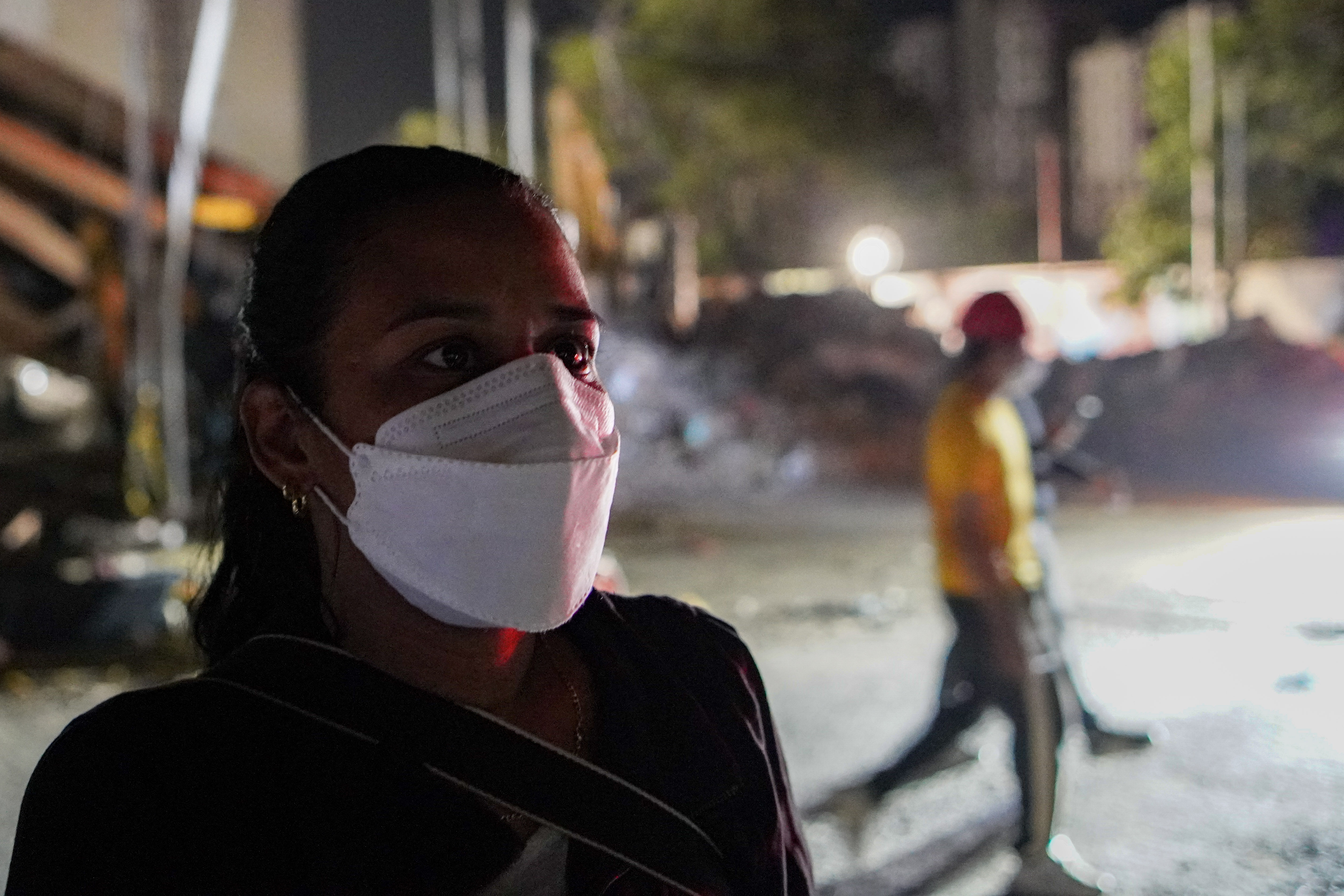 Daylin Arias pictured opposite the collapsed apartment building where her partner was last seen.