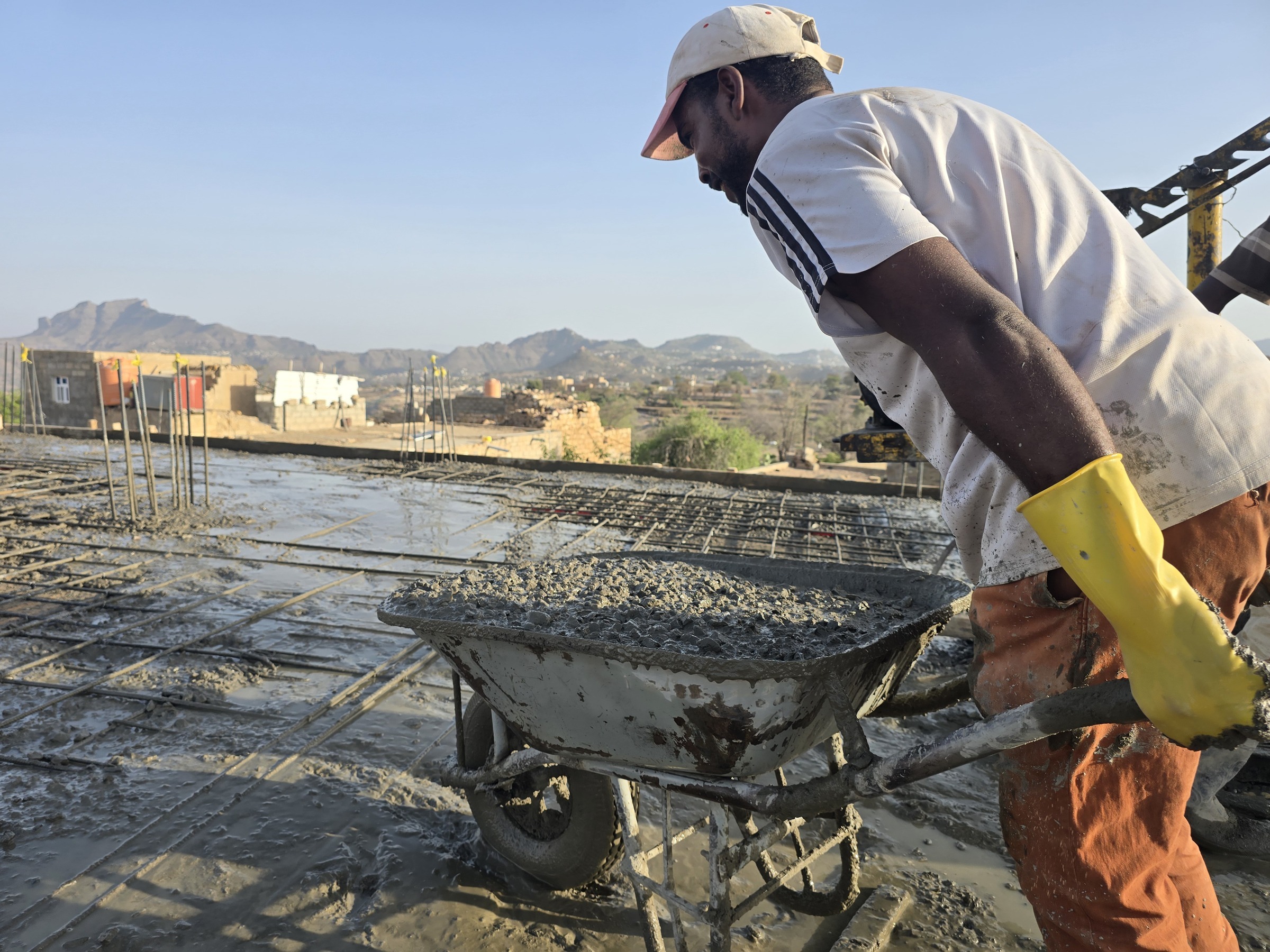 Construction labourers pour a concrete roof in Taiz governorate amid rising building material costs [Al Jazeera]