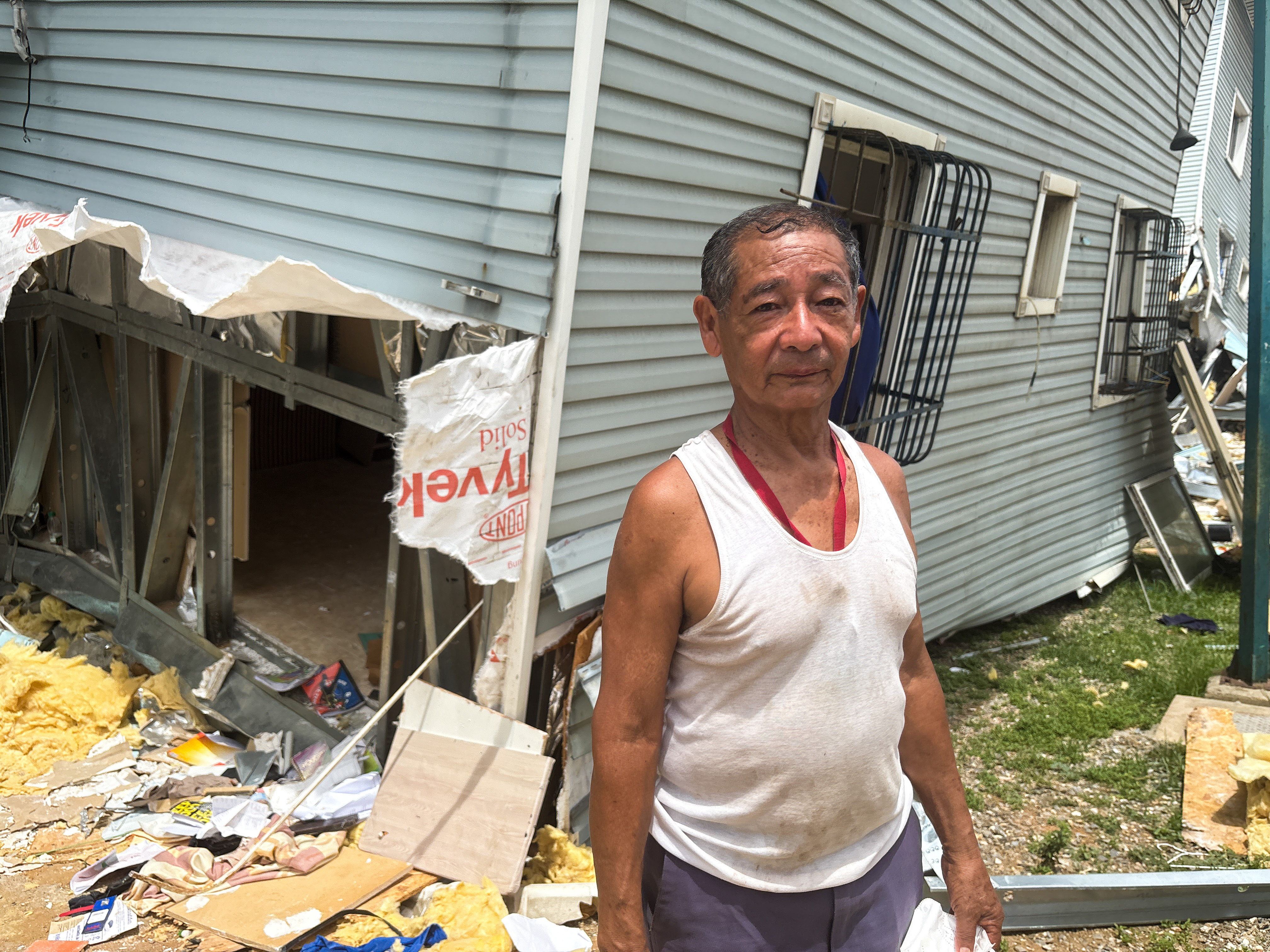 A resident of a government housing complex stands next to his destroyed home