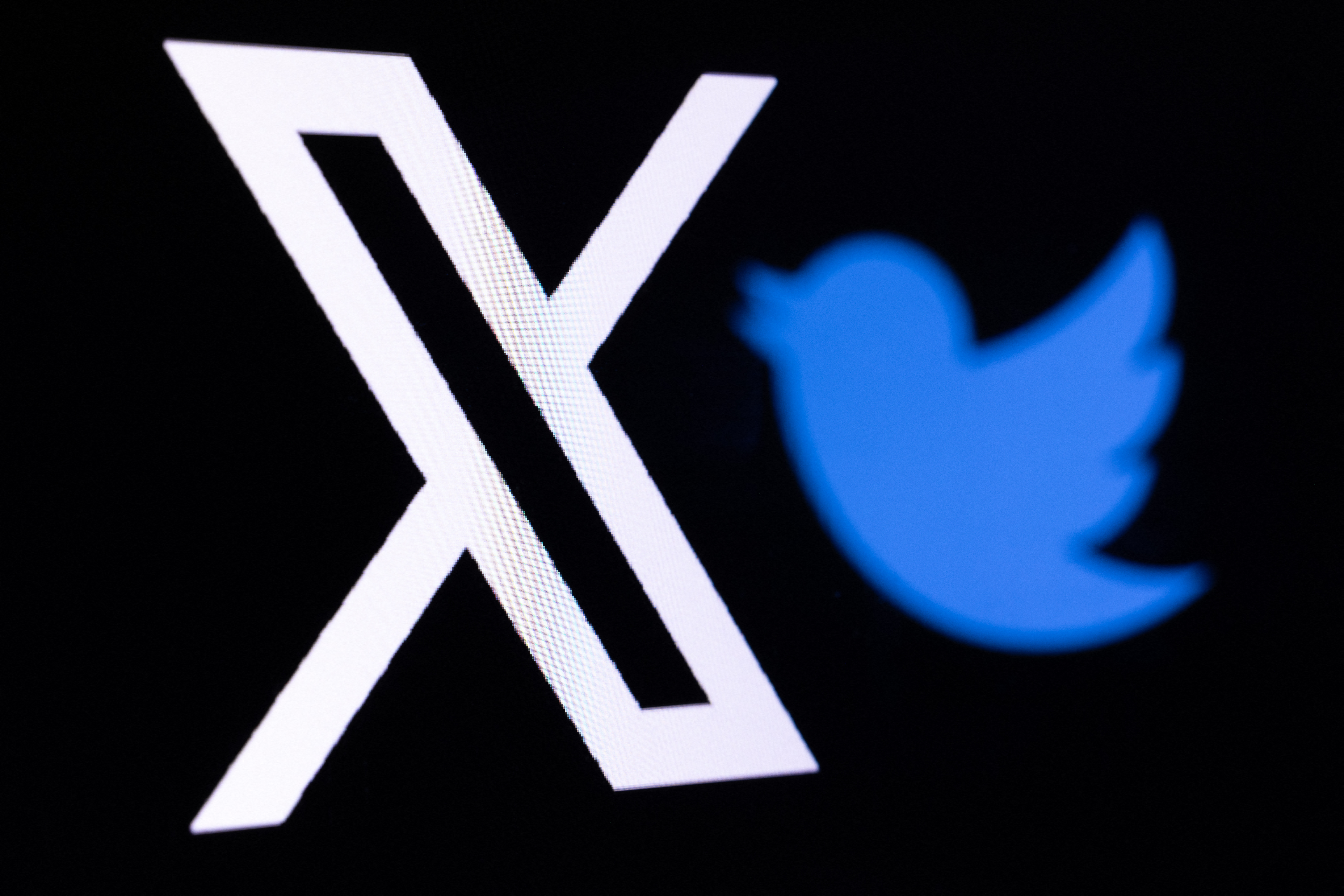 This illustration photo shows the new Twitter logo rebranded as X (L) and the old Twitter bird logo reflected in smartphone screens, in Paris on July 27, 2023