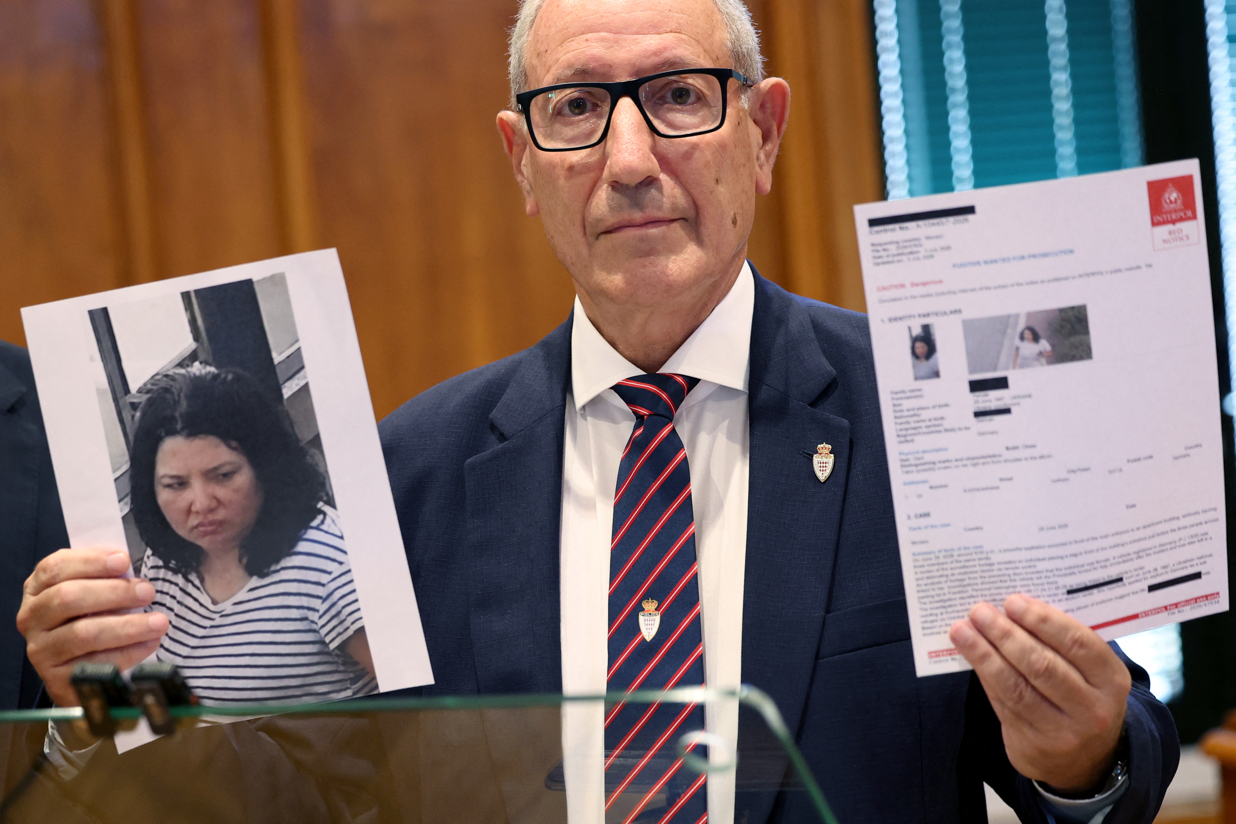 Monaco's Public Safety director Eric Arella holds up the red notice issued by Interpol against a Ukrainian woman suspected of planting a bomb in Monaco that injured three people, including a Ukrainian-born tycoon, during a press conference in Monaco on July 3, 2026.