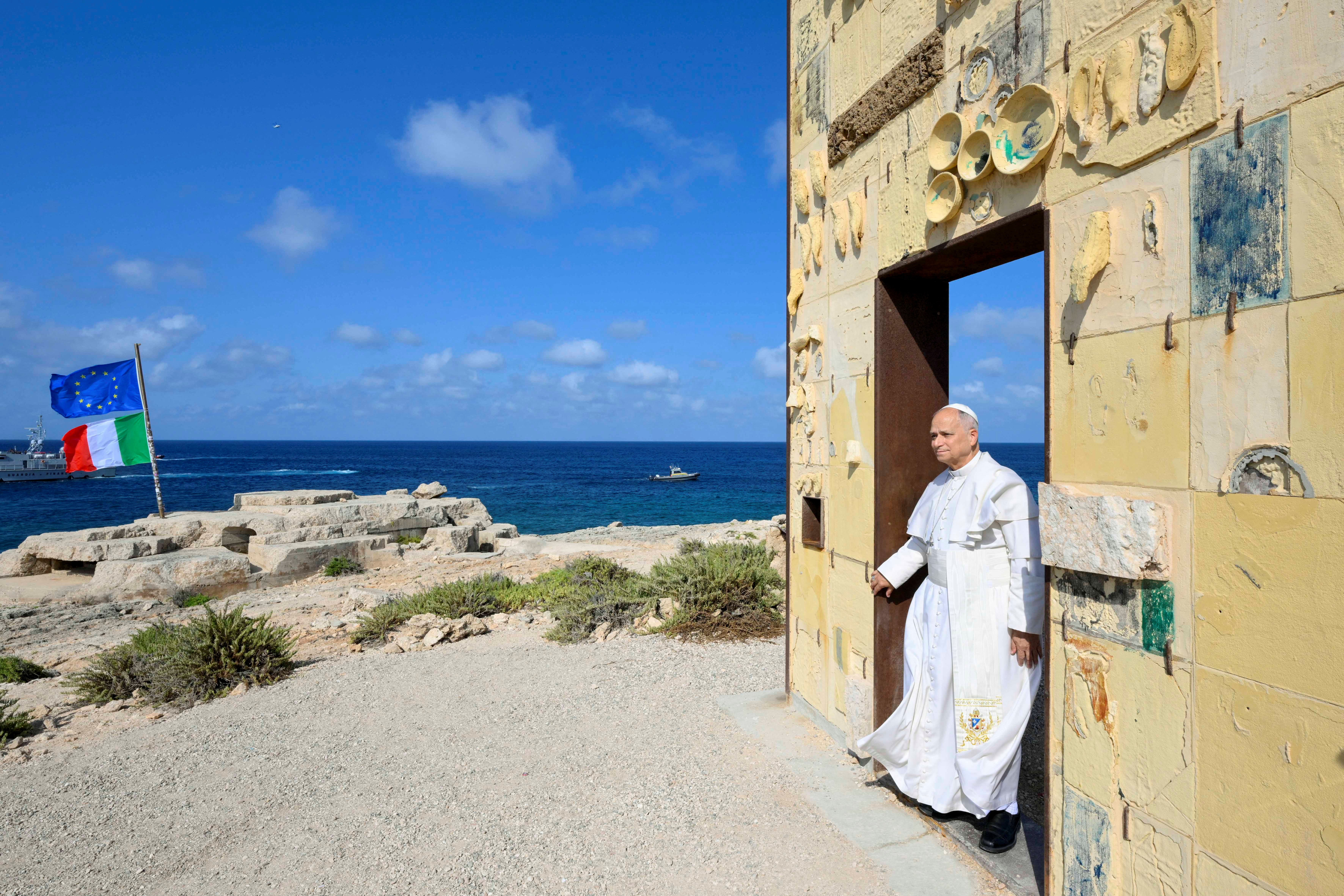 Pope Leo XIV walking through the arch of the monument Door of Europe - Porta d'Europa made by the italian artist Mimmo Paladino during a one day visit to Lampedusa island, south of Sicily. [Photo by VATICAN MEDIA / AFP]