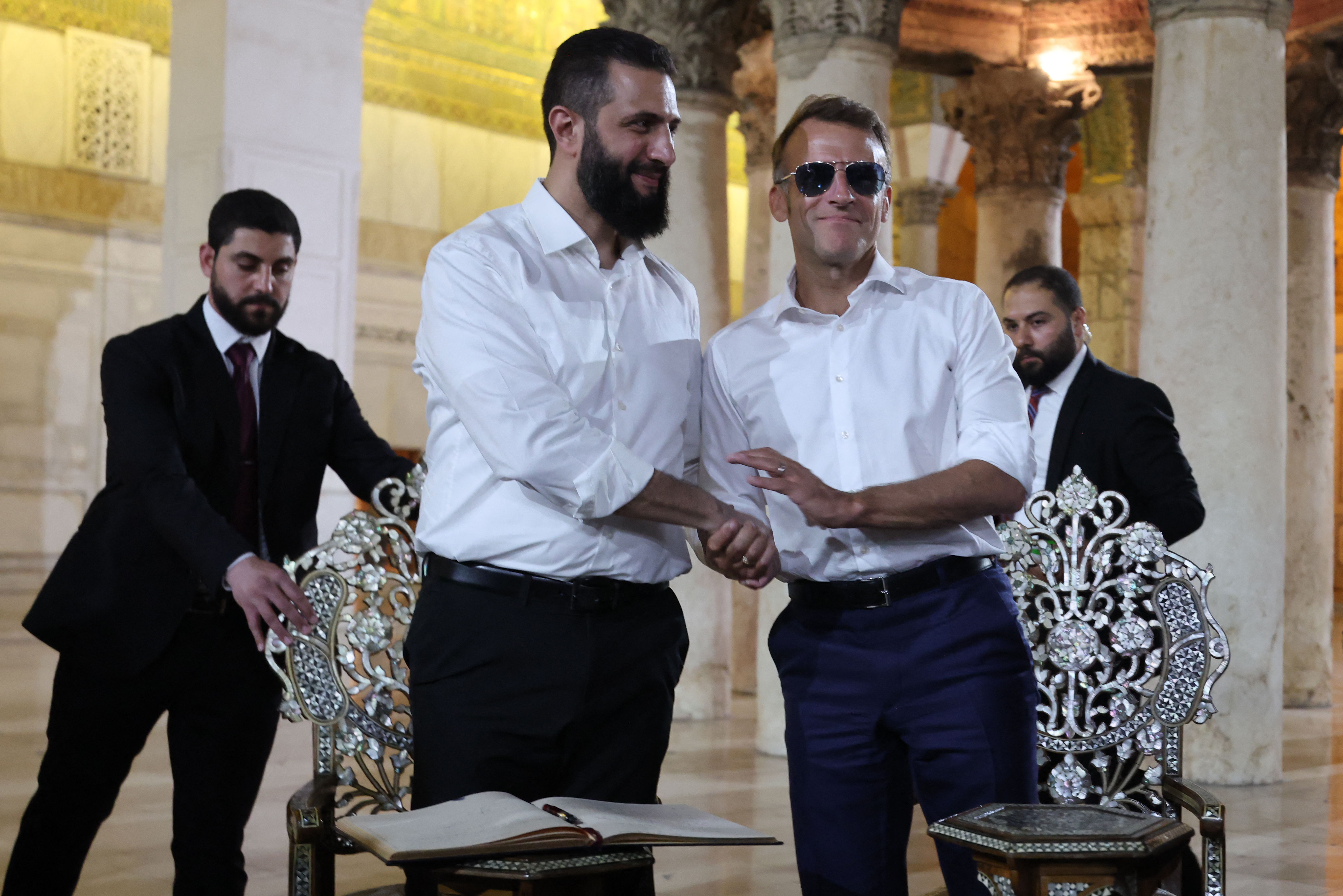 France's President Emmanuel Macron (R) shakes hands with Syrian President Ahmed Al-Charaa during a visit to the Umayyad Mosque in Damascus, on July 6, 2026. French President Emmanuel Macron arrived in Damascus on July 6, 2026 for the first visit by a Western European head of state since Syria's new authorities took power in 2024, an AFP journalist said. Macron, who will depart on July 7, 2026, will advocate for "a free, pluralist Syria that respects each of its components" and plays a role in moderating Middle East tensions, the French presidency told journalists ahead of his arrival. (Photo by Ludovic MARIN / POOL / AFP)