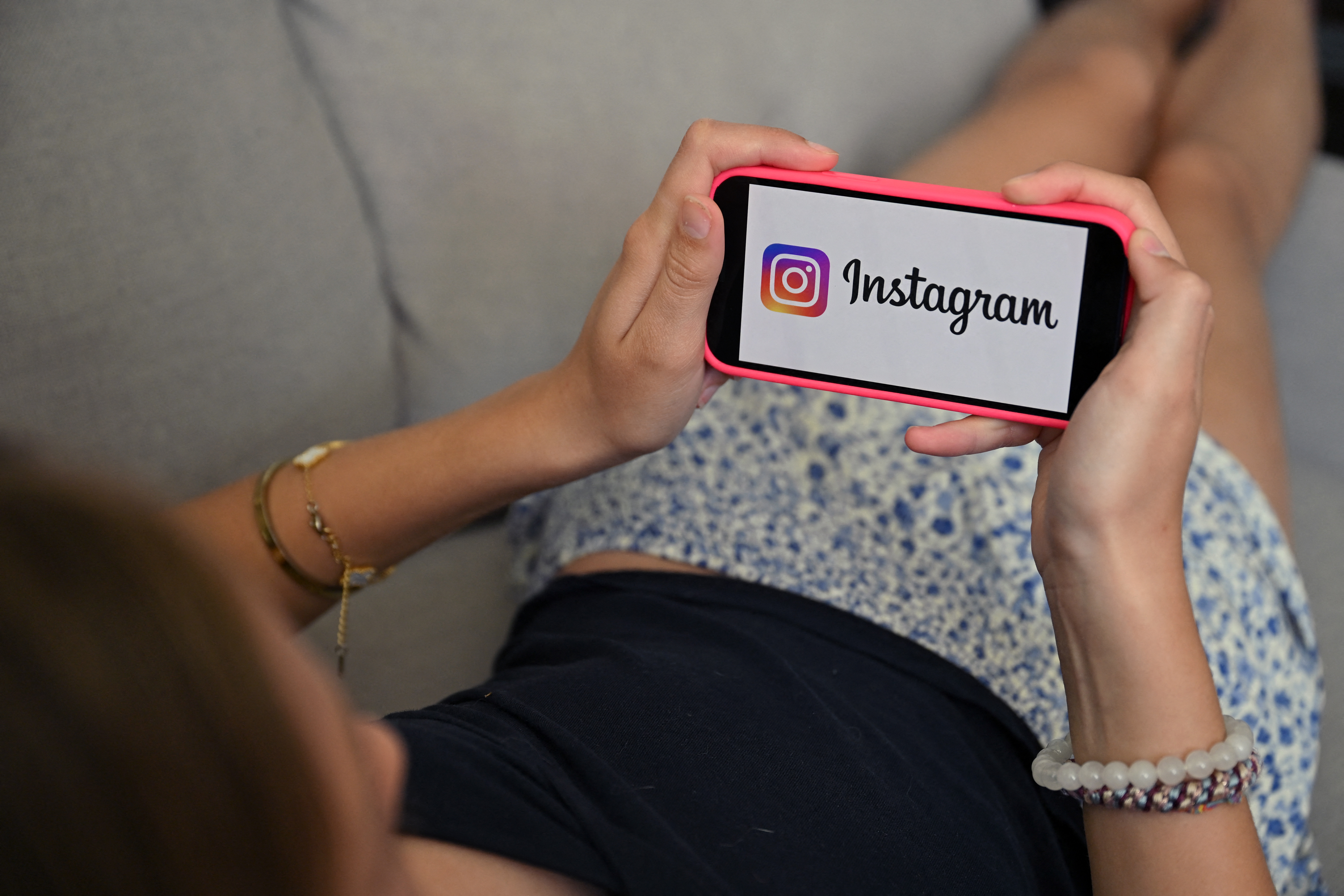 A teenager holds her smartphone displaying the logo of US social network Instagram in Brussels on July 7, 2026. The European Commission estimated, on July 6, 2026, that the French bill banning social media access for children under 15 was not fully compatible with European Union law, while reaffirming its support for the initiative. Like France, Spain and Denmark are also working on the introduction of a digital age of majority to follow Australia's example, who became in December 2025 the first country to implement such a law. (Photo by Nicolas TUCAT / AFP)