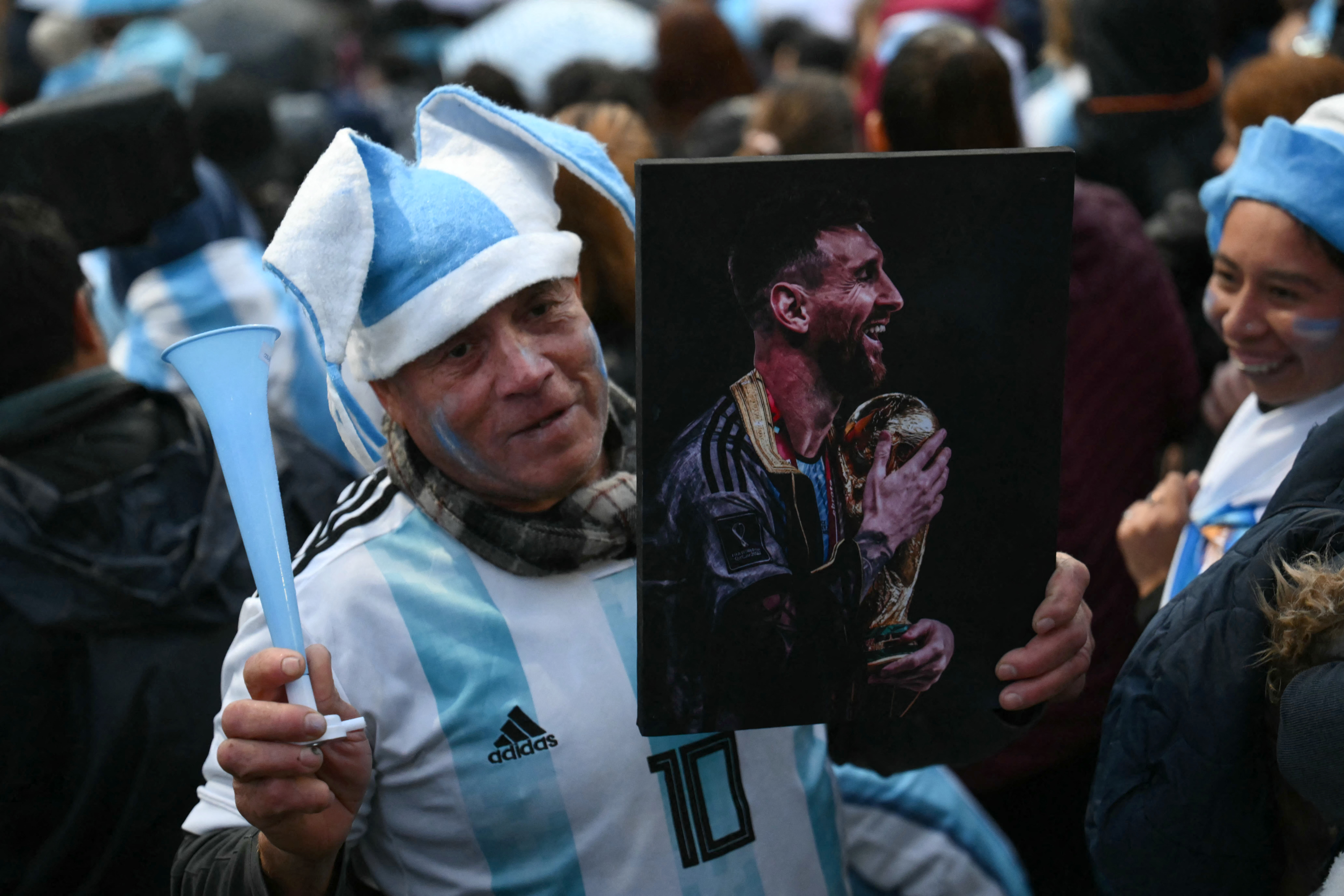 A fan holding a portrait of Argentina's forward Lionel Messi gathers near the Argentine Football Association (AFA) training camp in Ezeiza, Buenos Aires Province, on July 20, 2026, while waiting for the arrival of Argentina's national football team from the United States following its defeat in the 2026 FIFA World Cup final. (Photo by Luis ROBAYO / AFP)