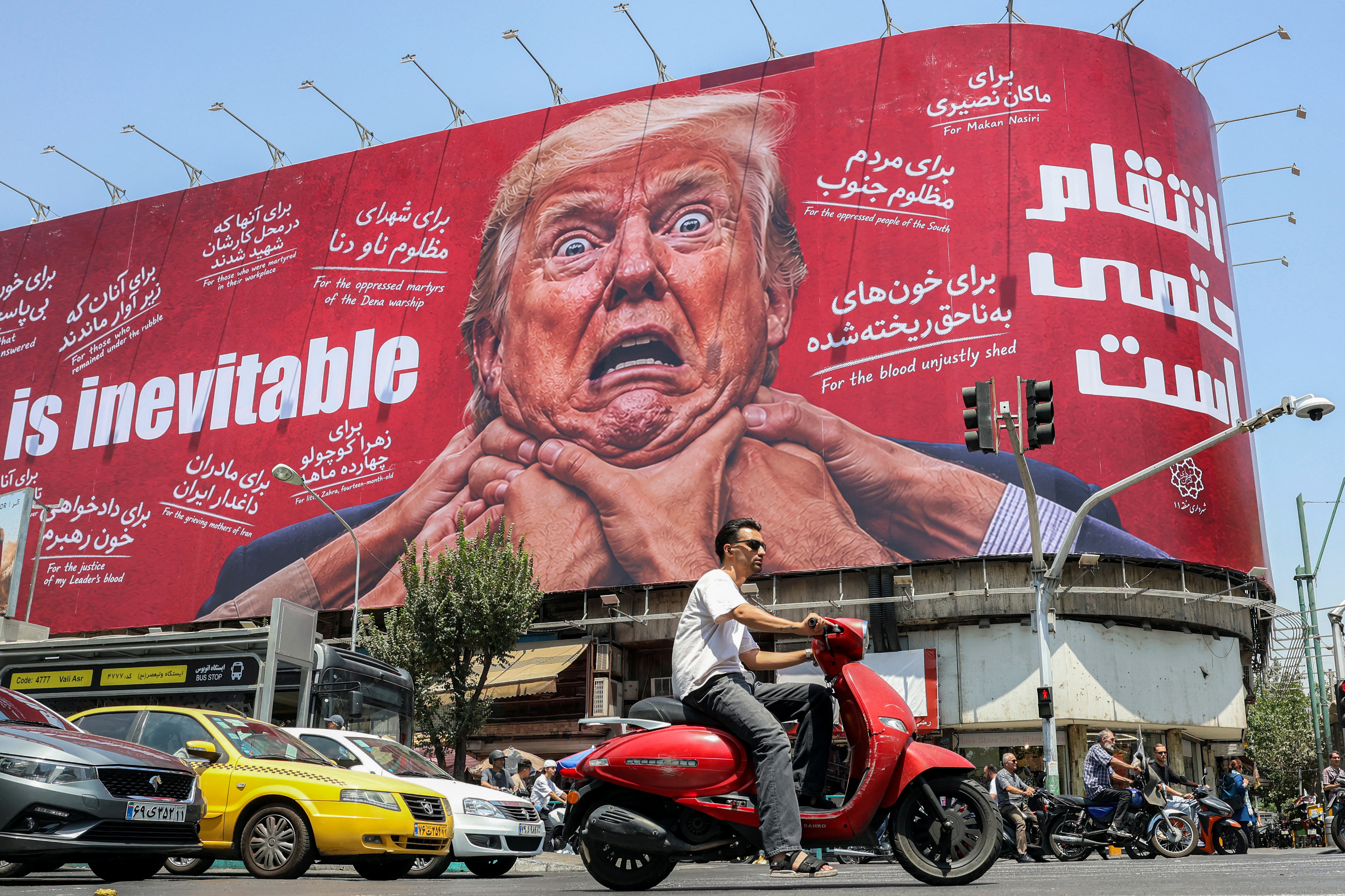 Motorists drive past a large billboard pledging revenge against US President Donald Trump in Tehran