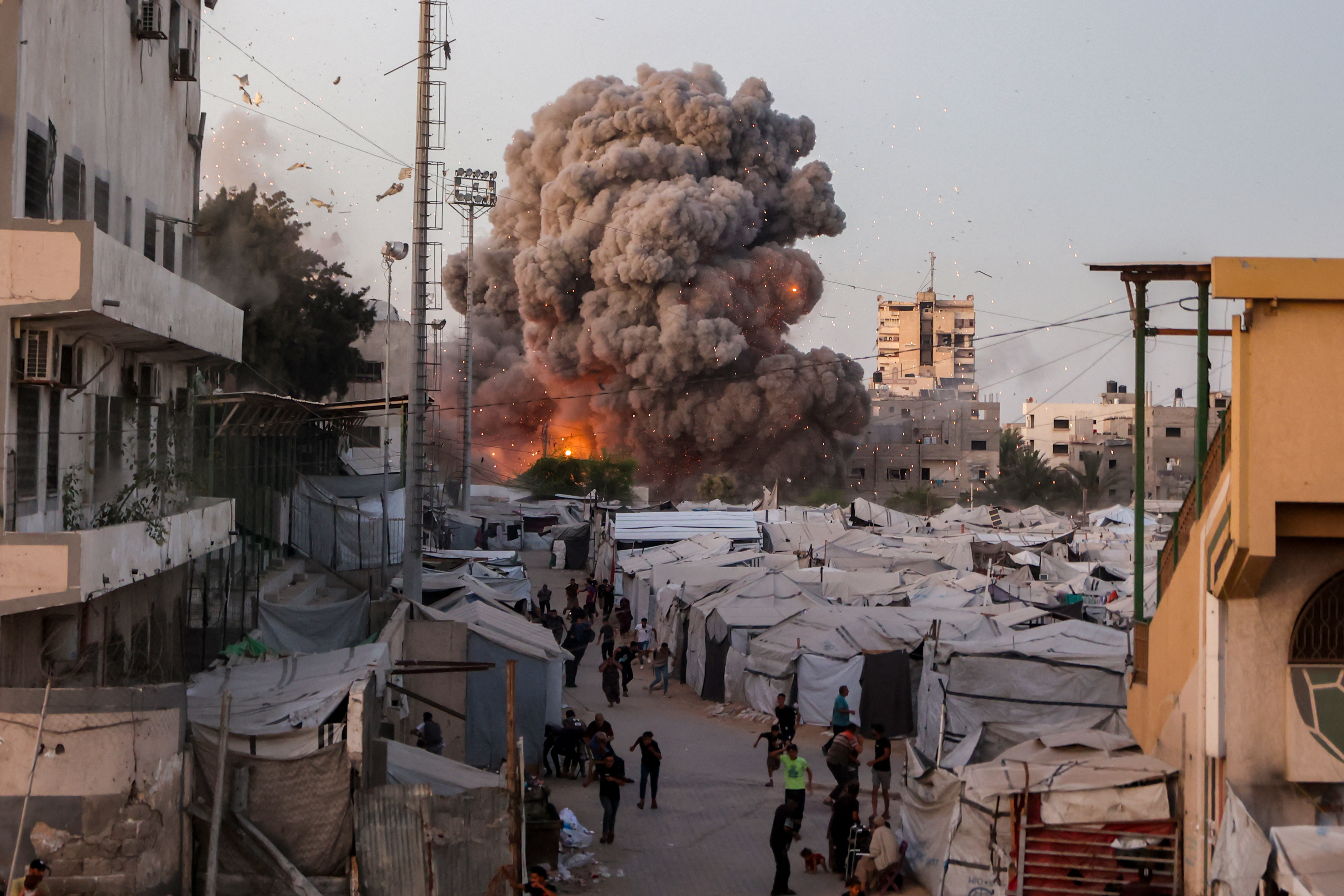 Palestinians run for cover as smoke and fire rise during an Israeli strike on the the Al-Muttaqin Mosque in Gaza City