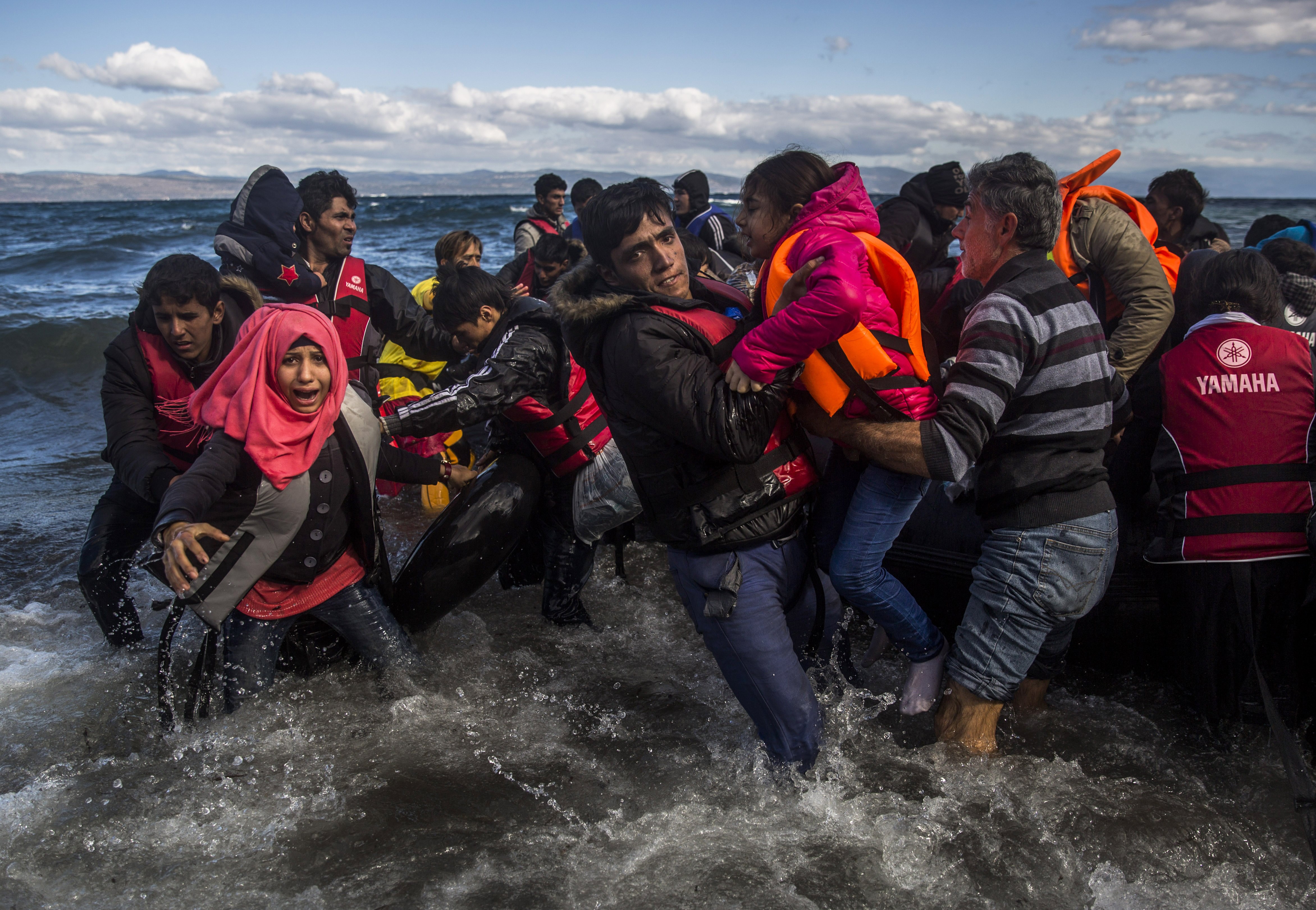migrants disembark safely from their frail boat in bad weather on the Greek island of Lesbos after crossing the Aegean see from Turkey