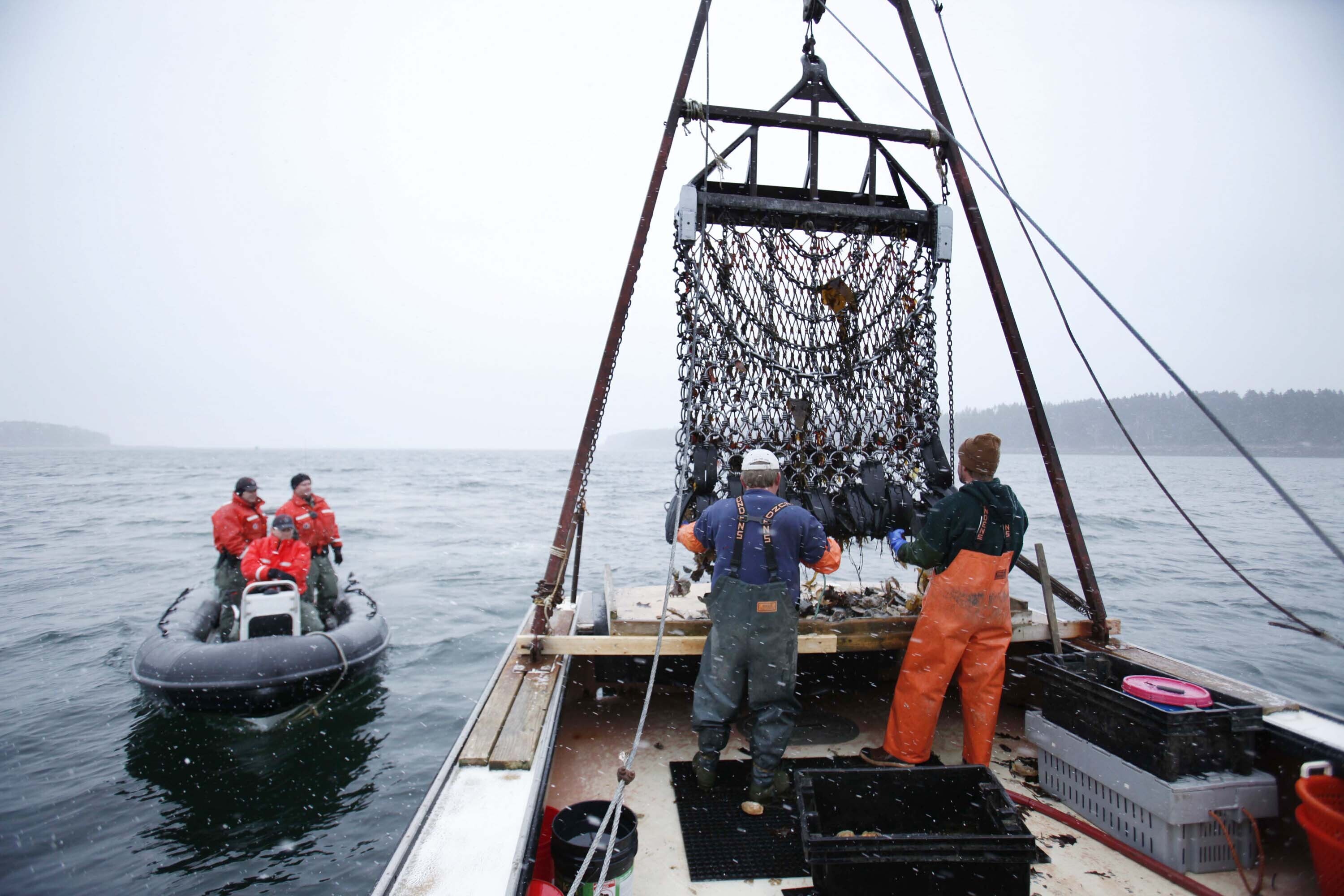 Marine Patrol officers, left, arrive for a routine inspection aboard scallop fisherman Donald Ricker's boat off Harpswell, Maine, US