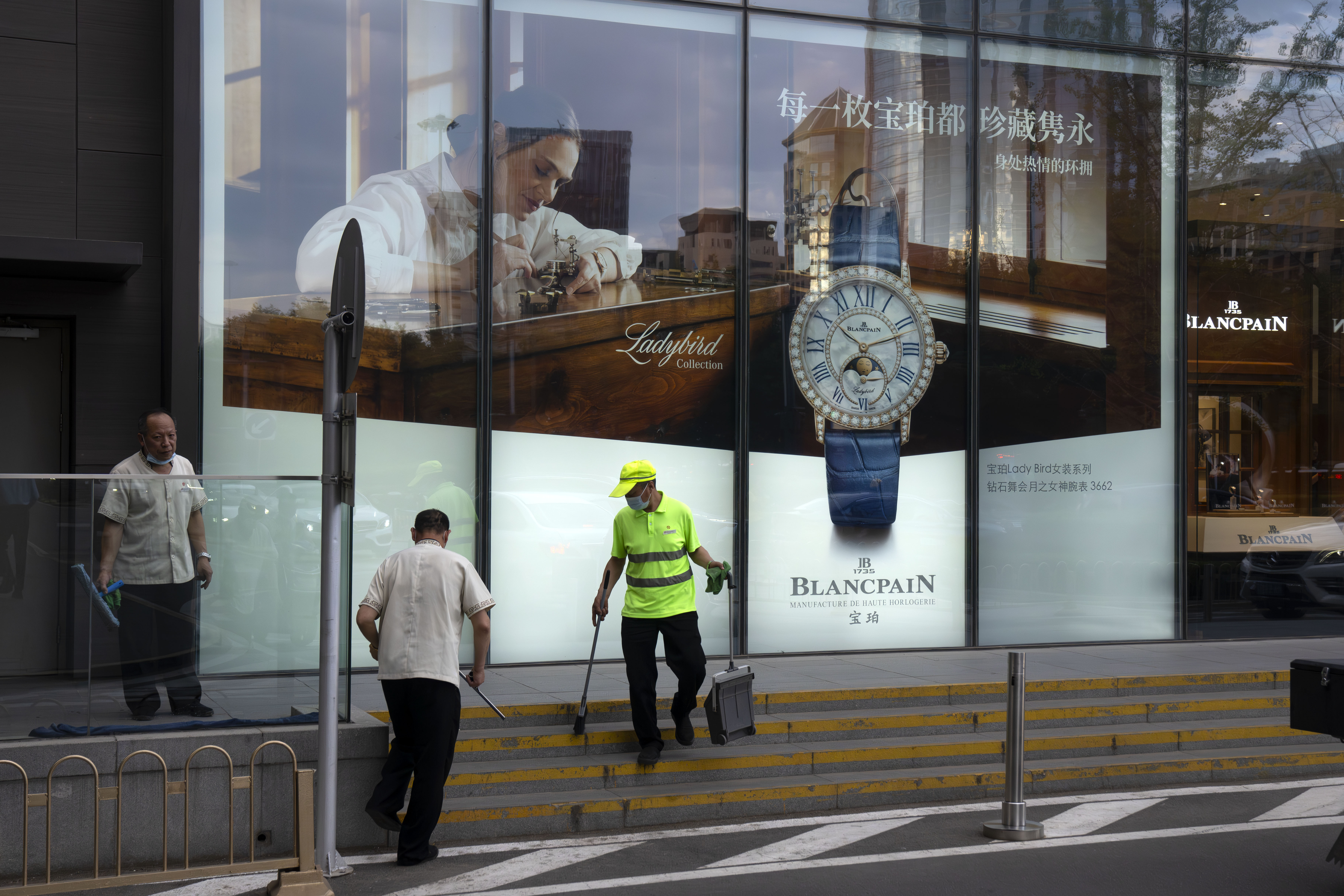 Cleaners work in front of an adveristing billboard for an upscale retailer at a shopping mall in the central business district in Beijing, Tuesday, June 13, 2023. China’s consumer and factory activity weakened in May and record-breaking unemployment among young people in cities rose as an economic rebound following the end of anti-virus controls slowed. (AP Photo/Mark Schiefelbein)