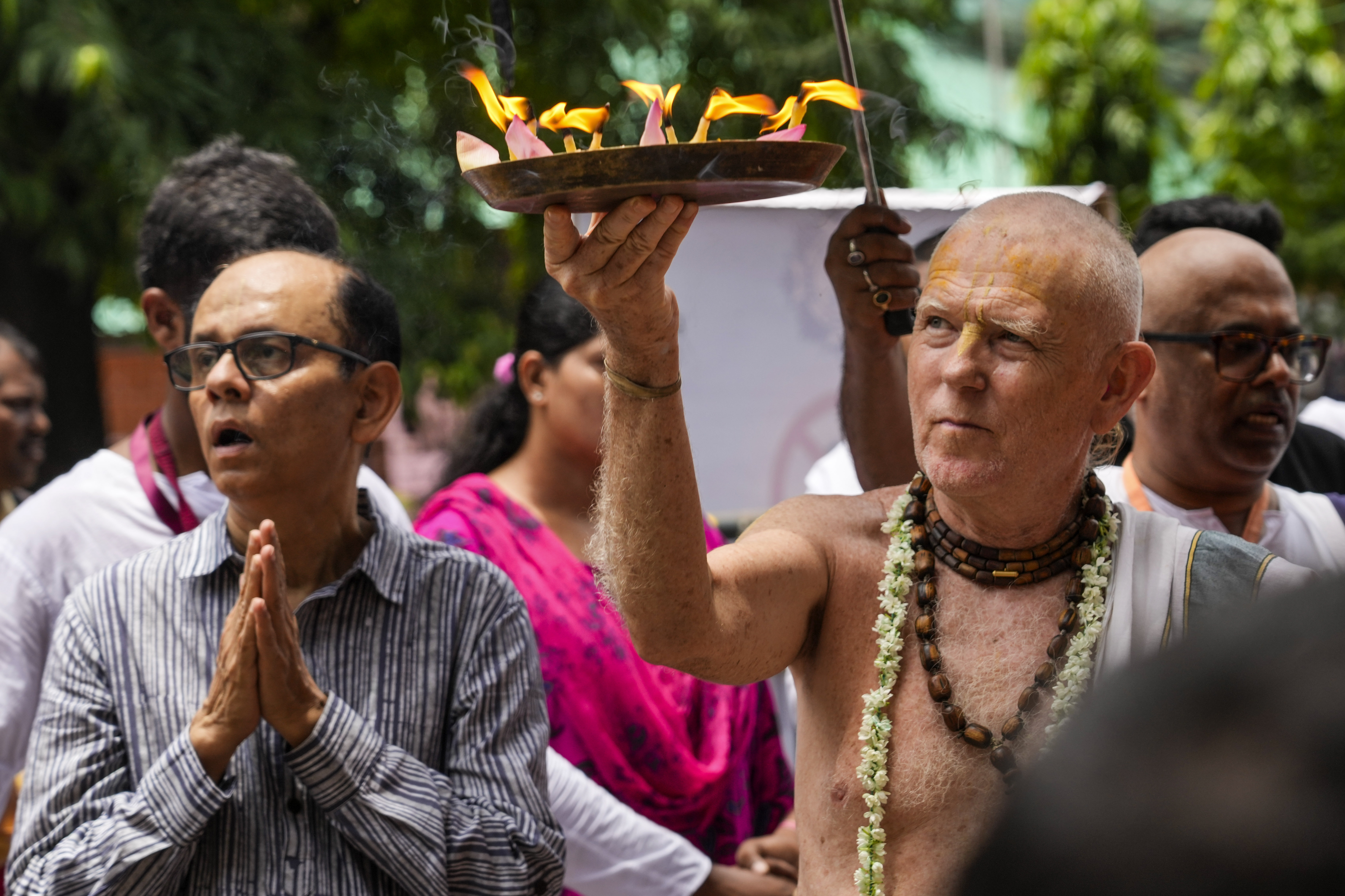 An elderly priest of International Society for Krishna Consciousness (ISKCON) offers a prayer with earthen lamps to Hindu god Jagannath during the return of the chariots festival in Kolkata, India, Monday, July 15, 2024. The return of the chariots marks the end of the nine-day long chariot festival. (AP Photo/Bikas Das)