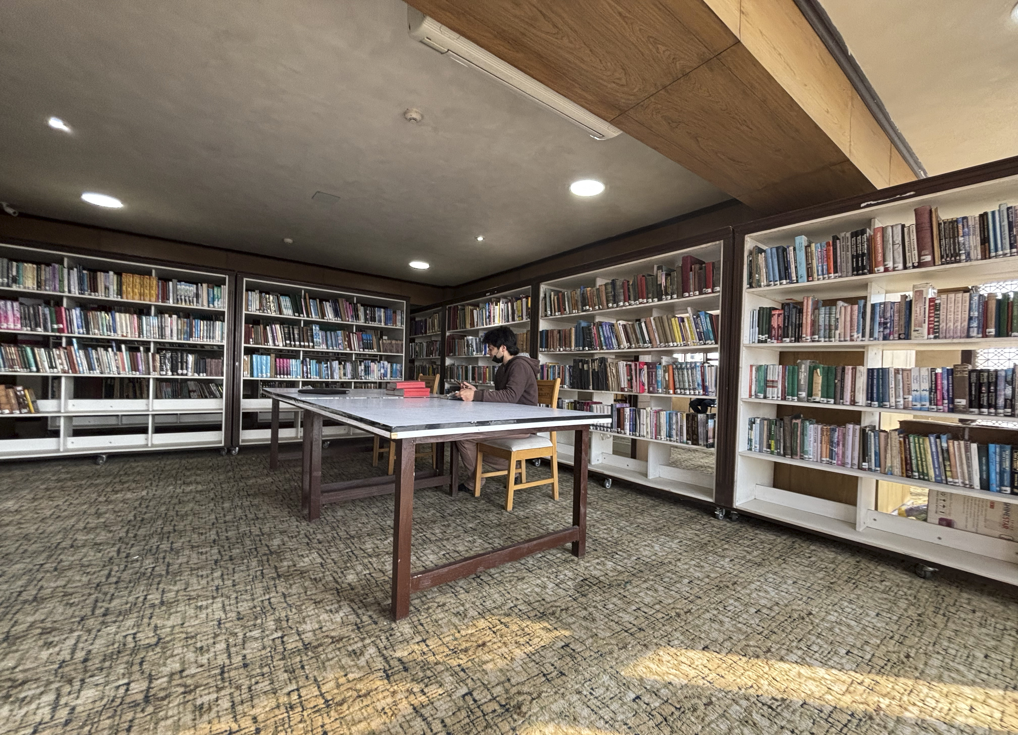 A man reads a book inside a library in Srinagar, February 17, 2025