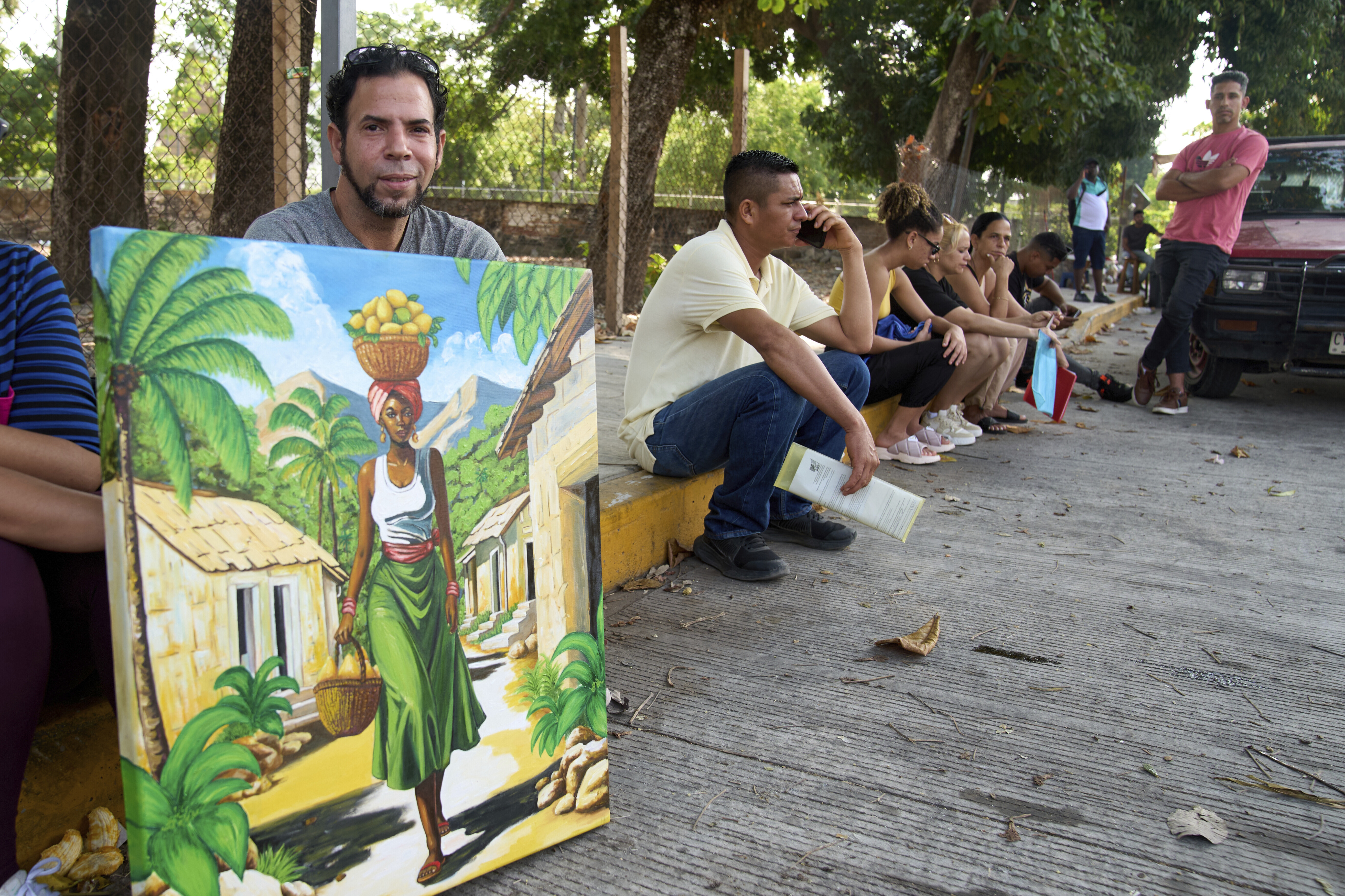 Cuban asylum seeker Junior Rodríguez Santos holds up a piece of art he painted outside the Mexican Commission for Refugee Aid (COMAR) in Tapachula, Chiapas state, Mexico, Wednesday, March 12, 2025. (AP Photo/Moises Castillo)