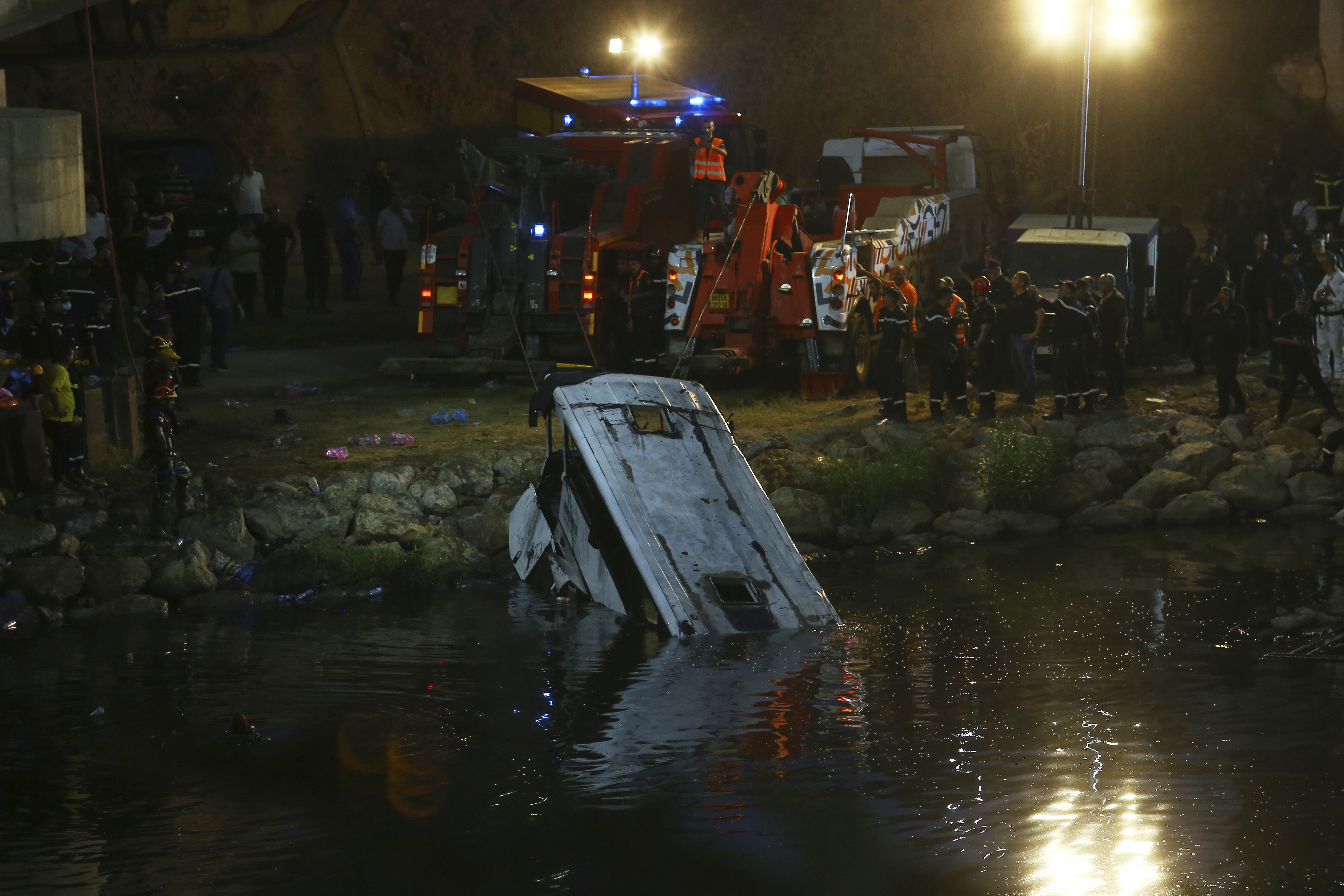 A passenger bus that plunged into a river is towed by rescue workers on August 15, 2025 in the El Harrach district of Algiers, Algeria.