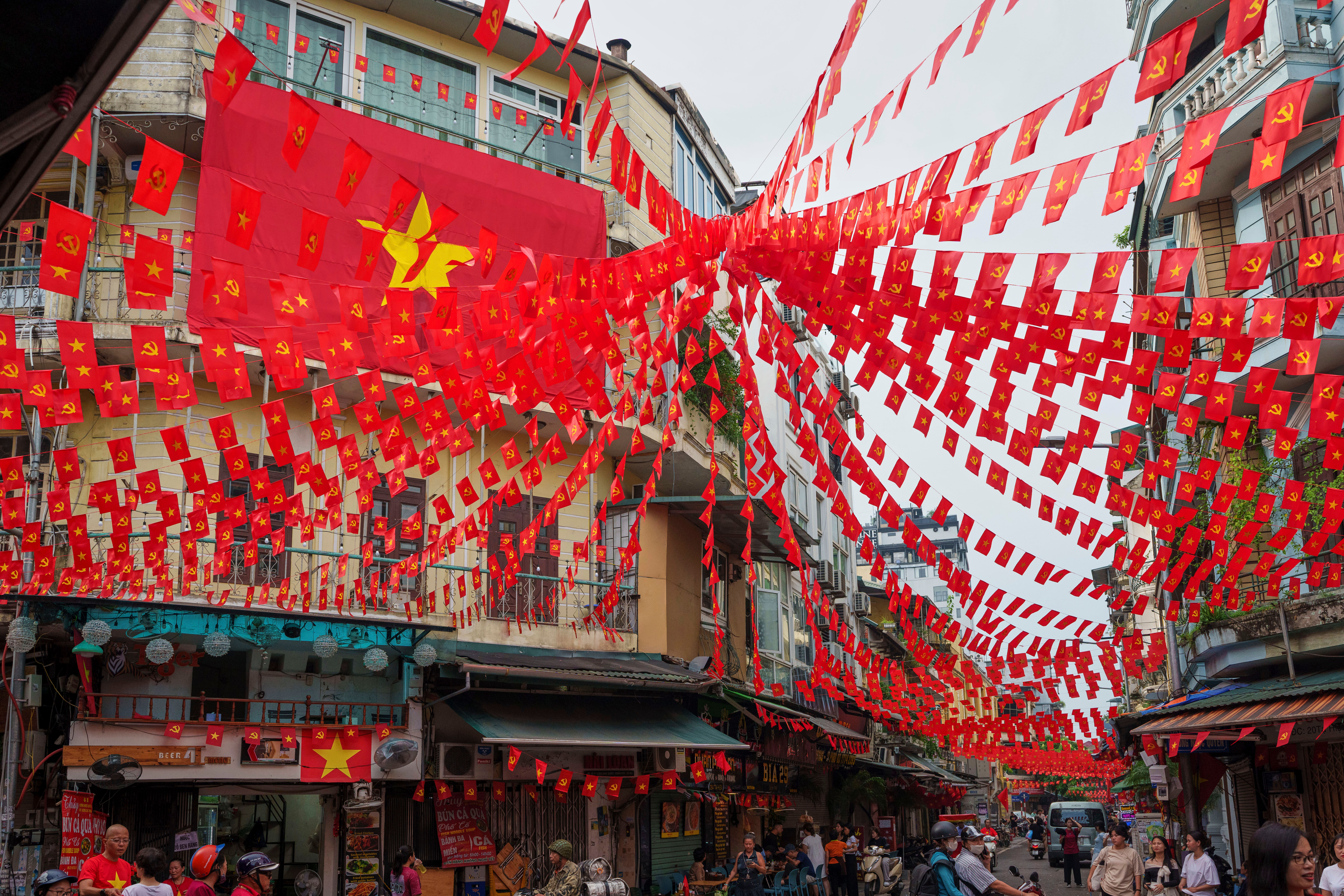 Vietnamese and communist flags hang from balconies across streets in the old quarter of Hanoi, Vietnam, on September 1, 2025