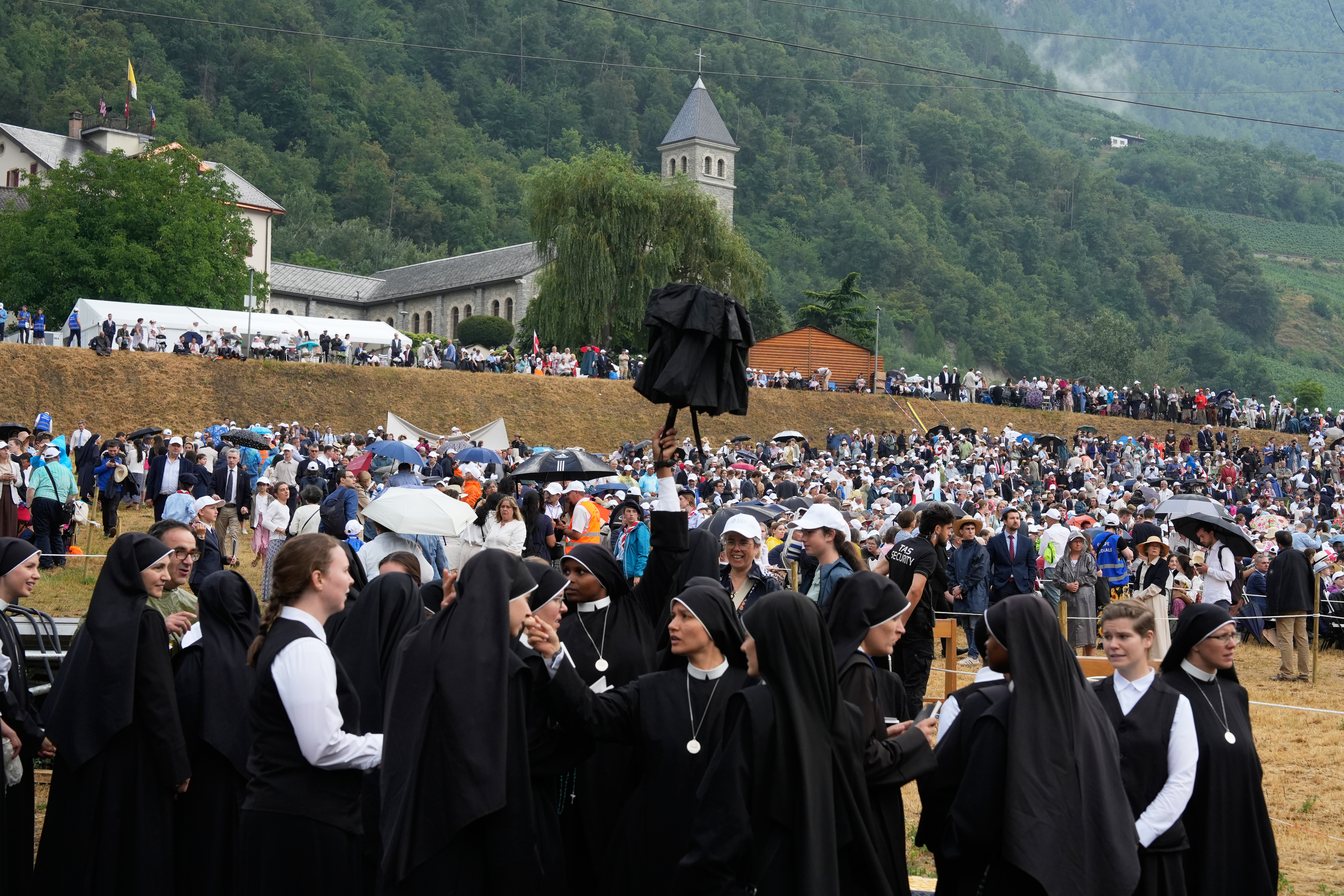 Faithful gather in front of a tent set up outside the Society of St. Pius X seminary to attend a consecration ceremony for four new bishops in Econe