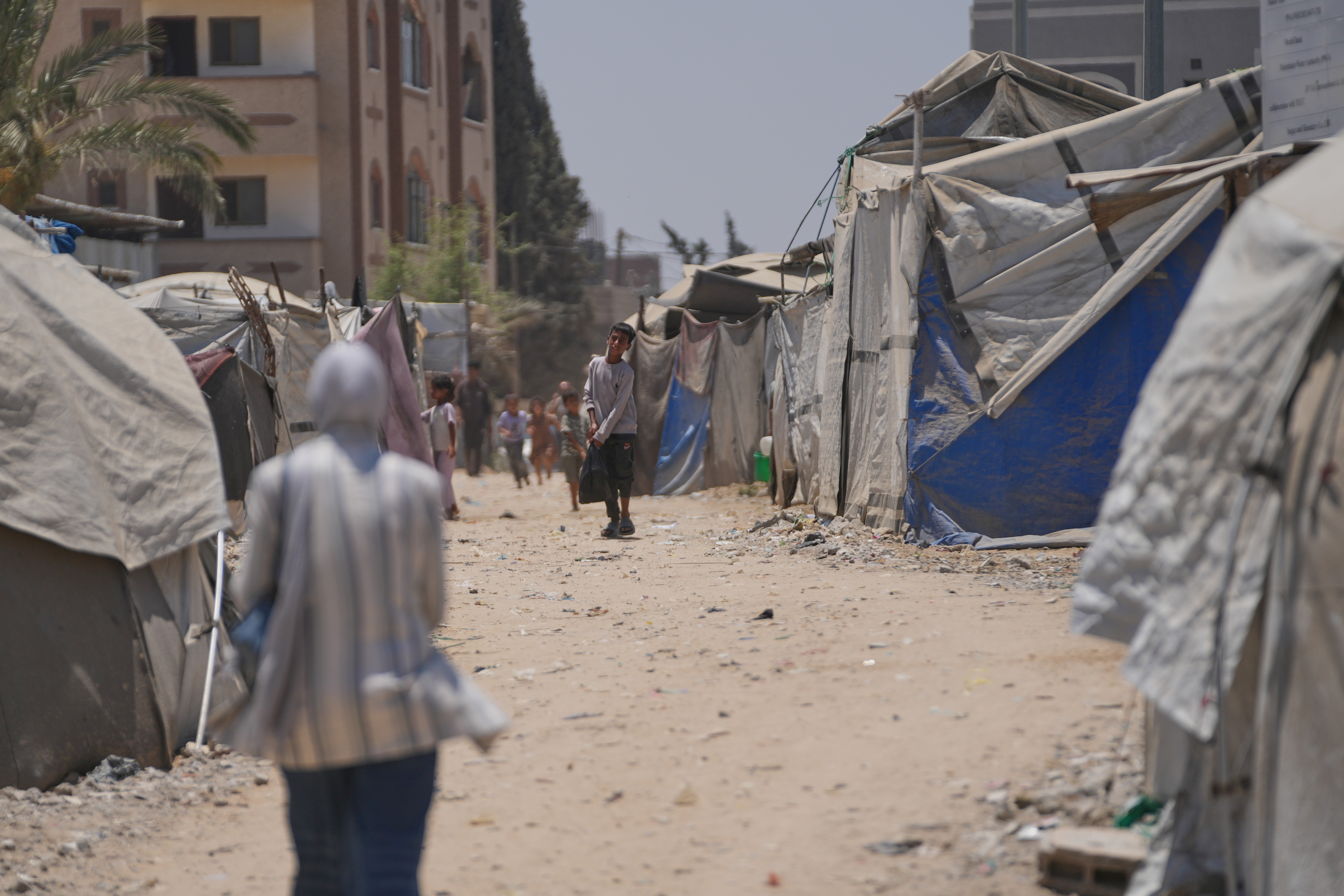 Displaced Palestinians walk between tents in Deir al-Balah, central Gaza on July 4, 2026.