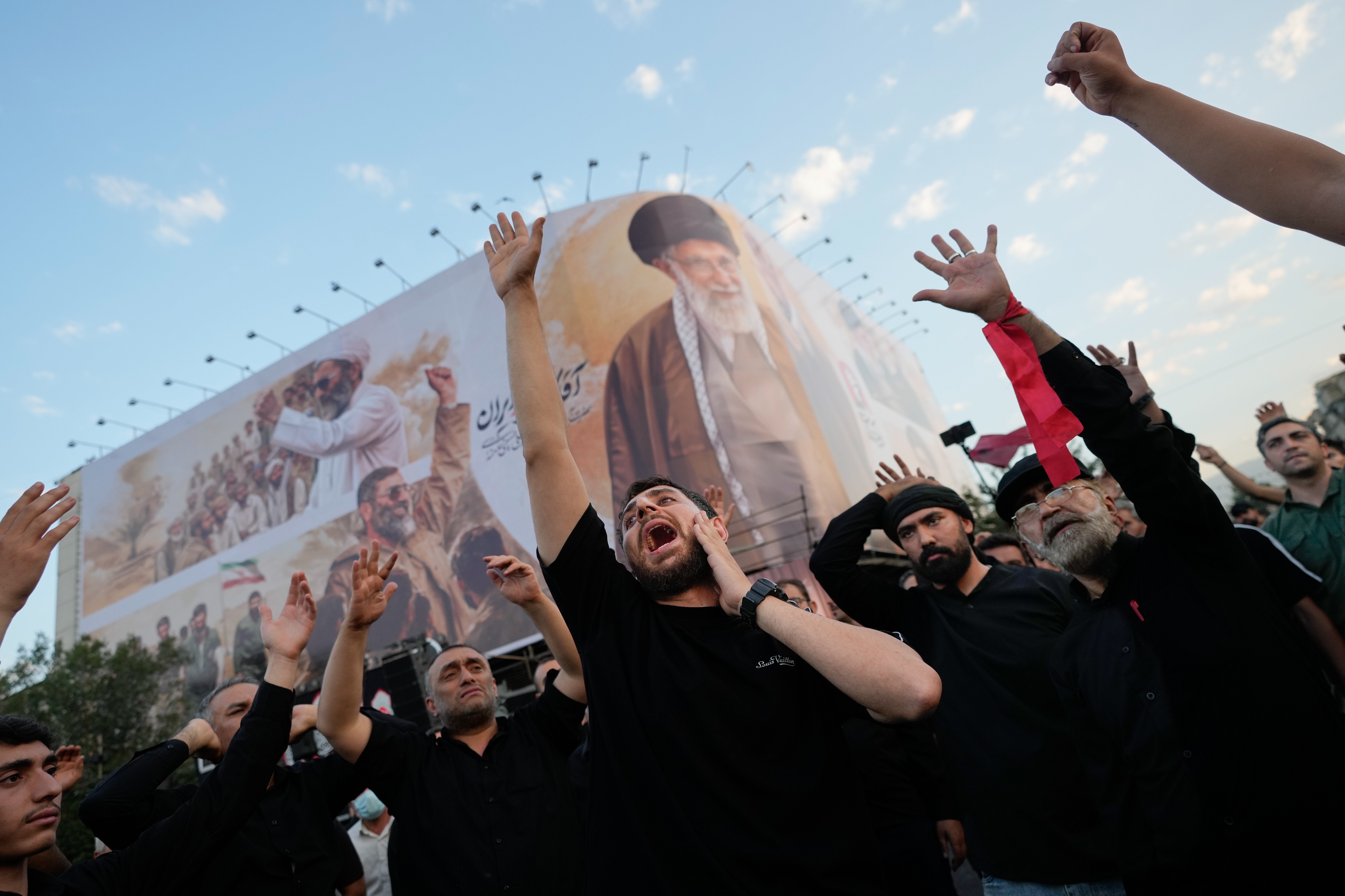 Mourners chant slogans while gathered in Islamic Revolution Square for the funeral procession of the slain Iranian Supreme Leader Ayatollah Ali Khamenei beneath a billboard depicting Khamenei in Tehran, Iran, Monday, July 6, 2026. (AP Photo/Altaf Qadri)