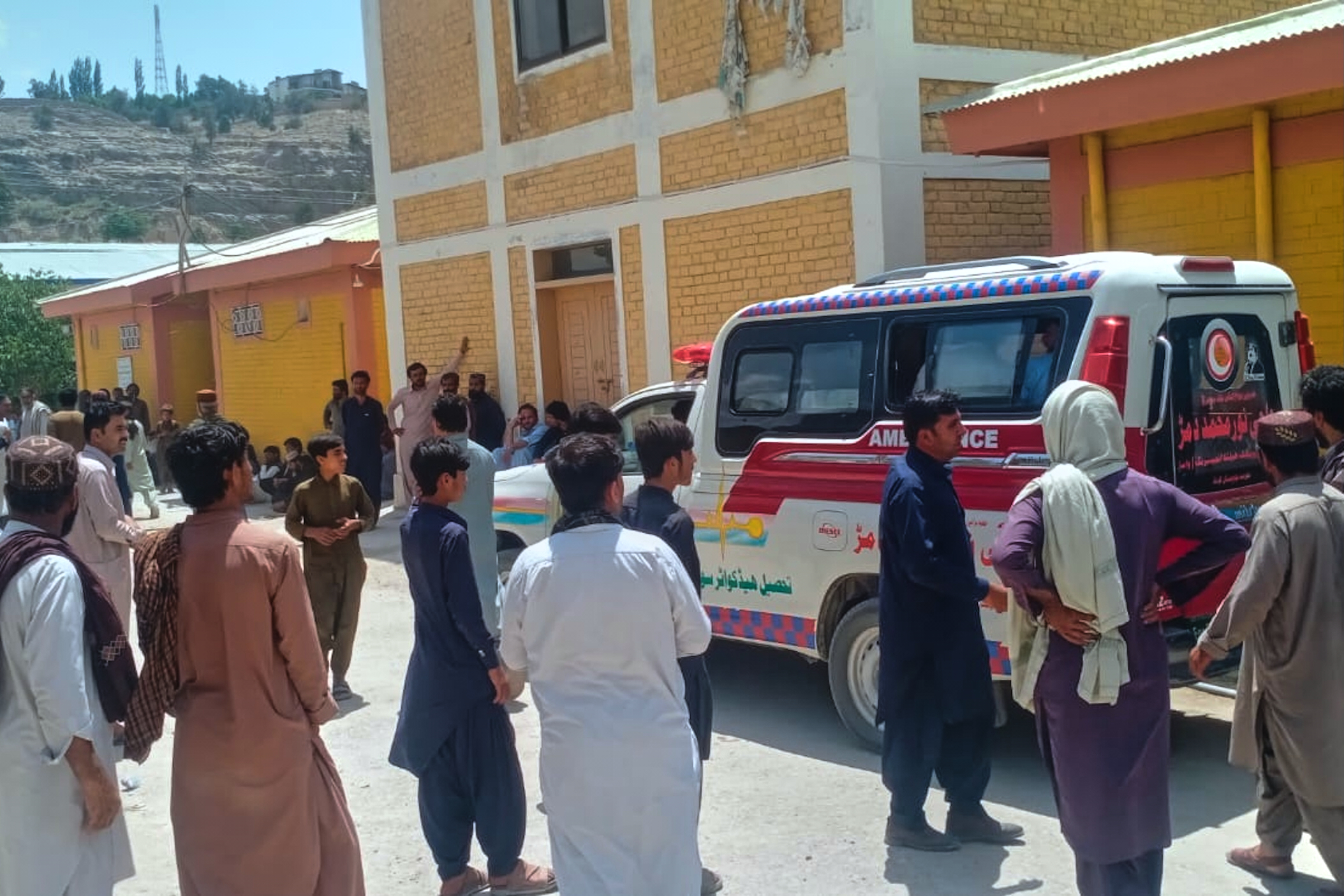 People stand near ambulances.