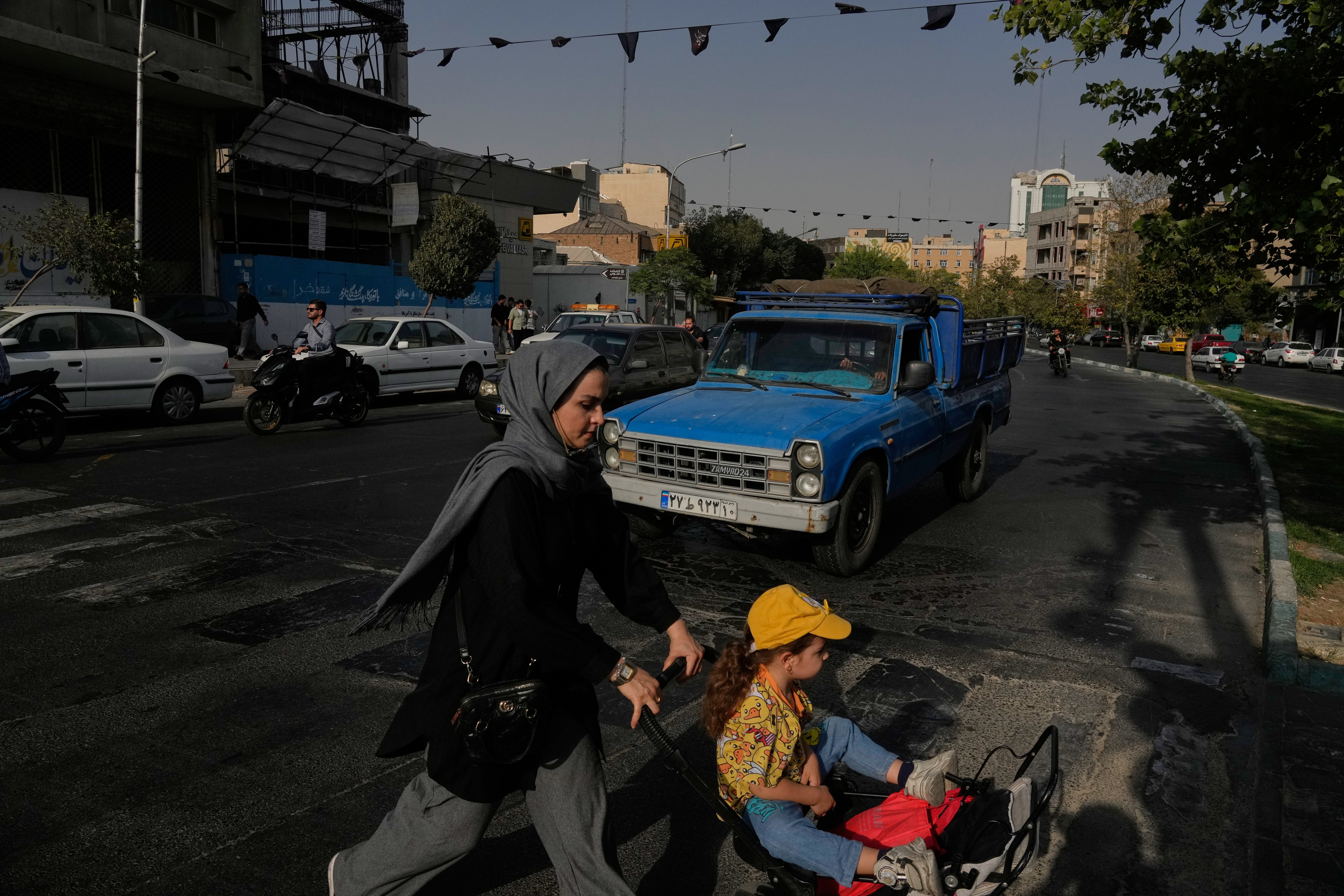 A woman and girl cross a street in central Tehran on July 22, 2026