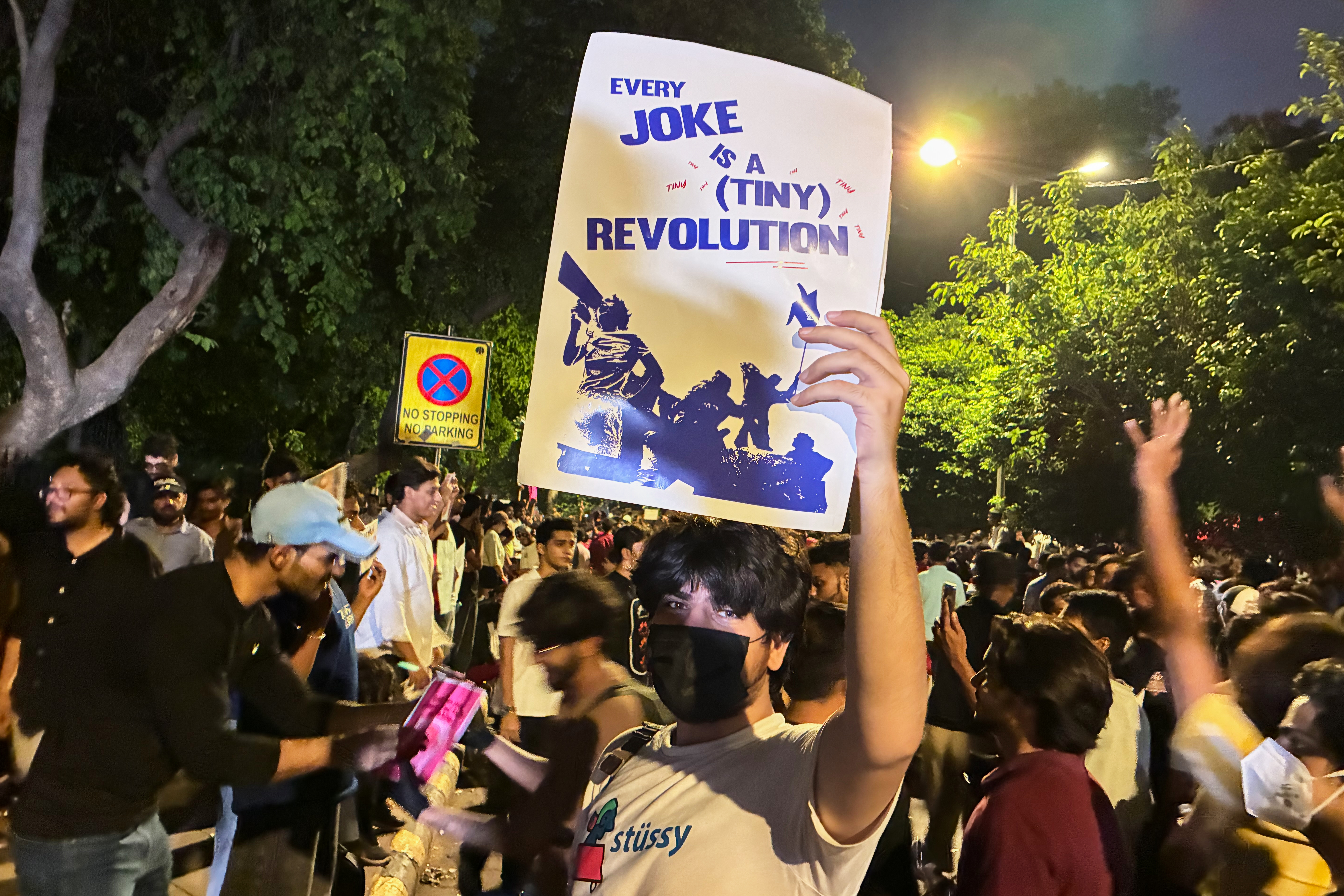 A protester holds a placard with the message "Every Joke is a Tiny Revolution" during a demonstration demanding educational reforms as part of the Cockroach Janta Party's ongoing protest movement in New Delhi, India on July 23, 2026.