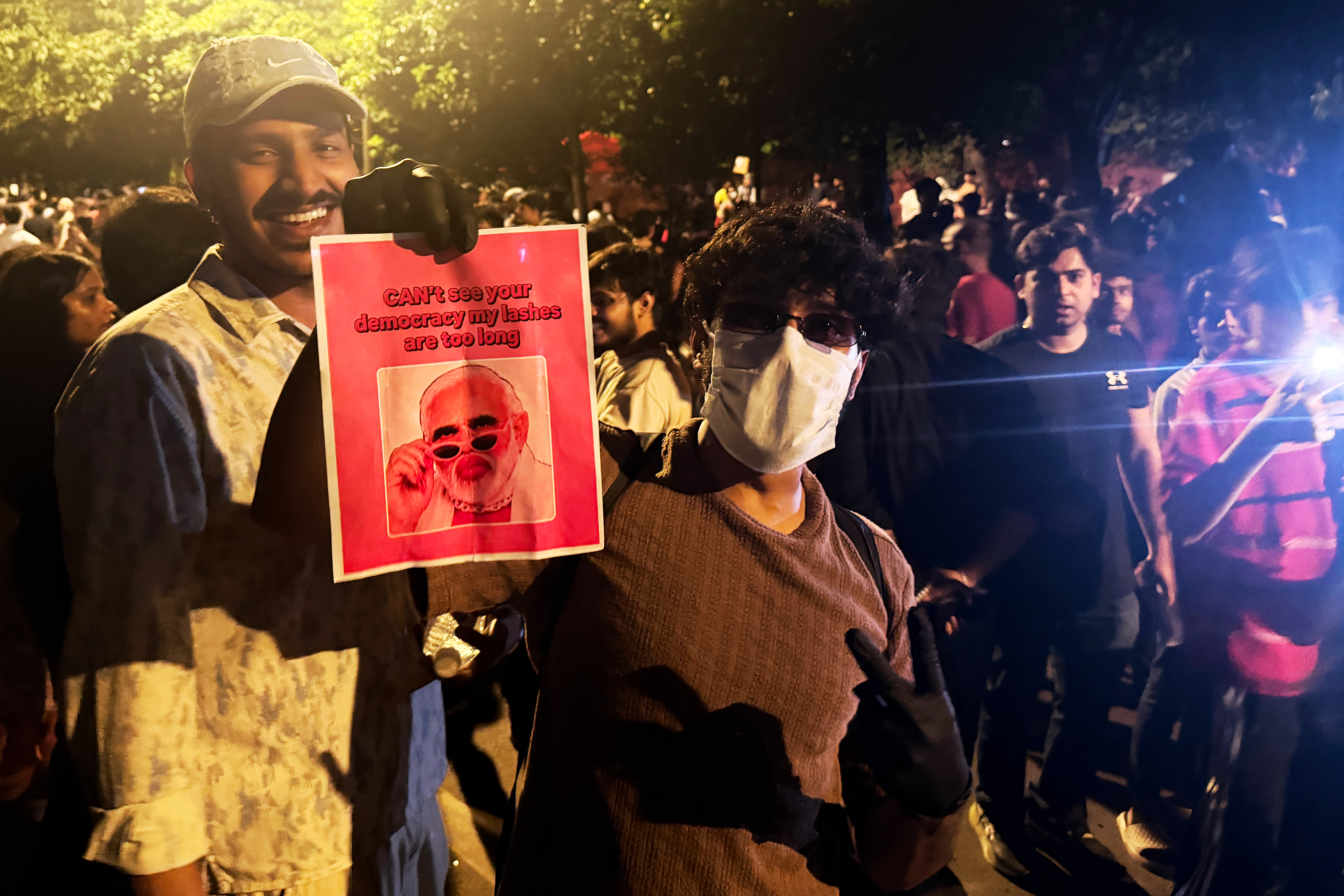 A protester holds a placard with a portrait of Prime Minister Narendra Modi along with the text "Can't See Your Democracy, My Lashes are Too Long" during a demonstration as part of the Cockroach Janta Party's ongoing protest movement in New Delhi, India on July 23, 2026.