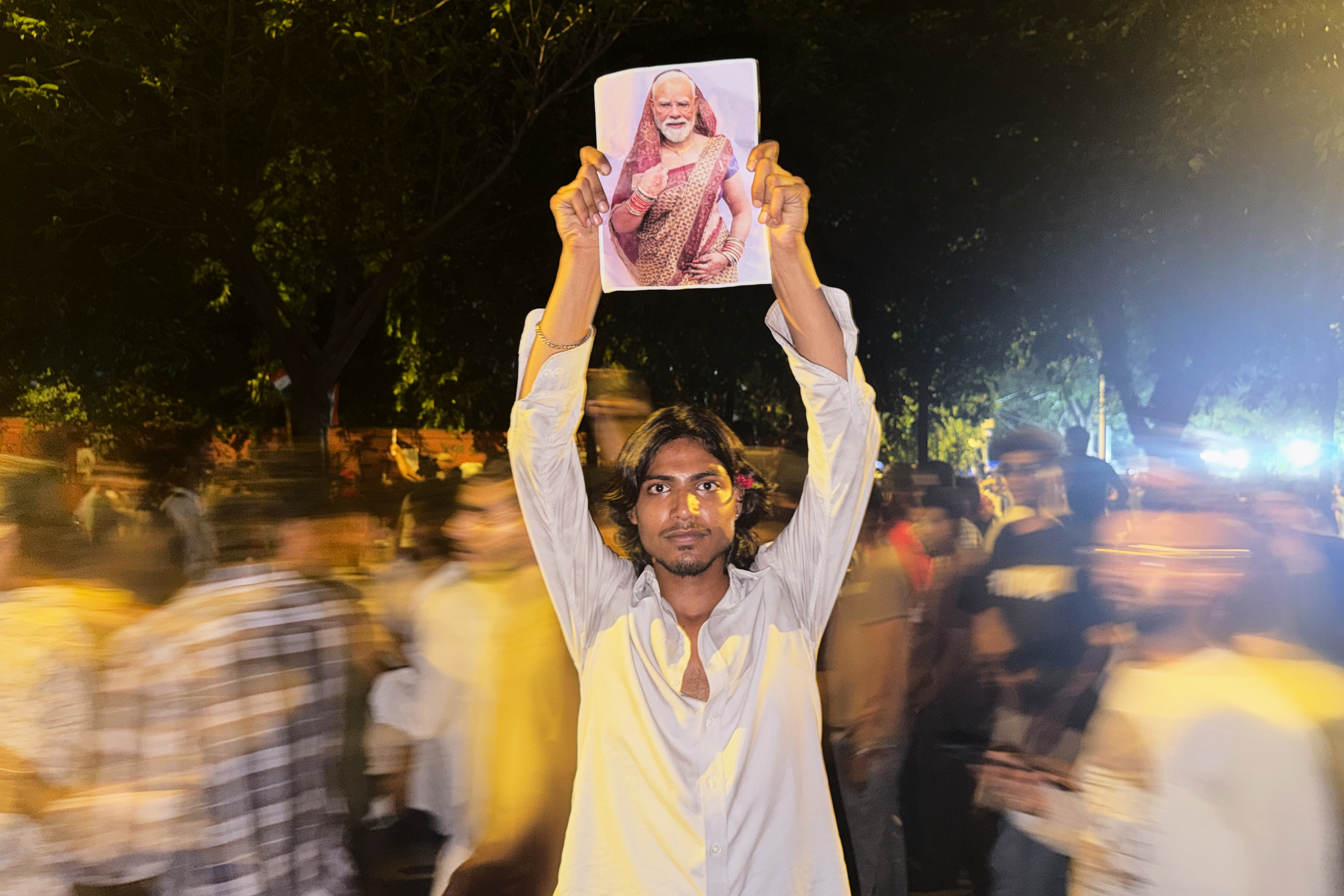 A protester holds a placard with a portrait of Indian Prime Minister Narendra Modi draped in a saree, a traditional garment for women in India, during a demonstration as part of the Cockroach Janta Party's ongoing protest movement in New Delhi, India on July 23, 2026.