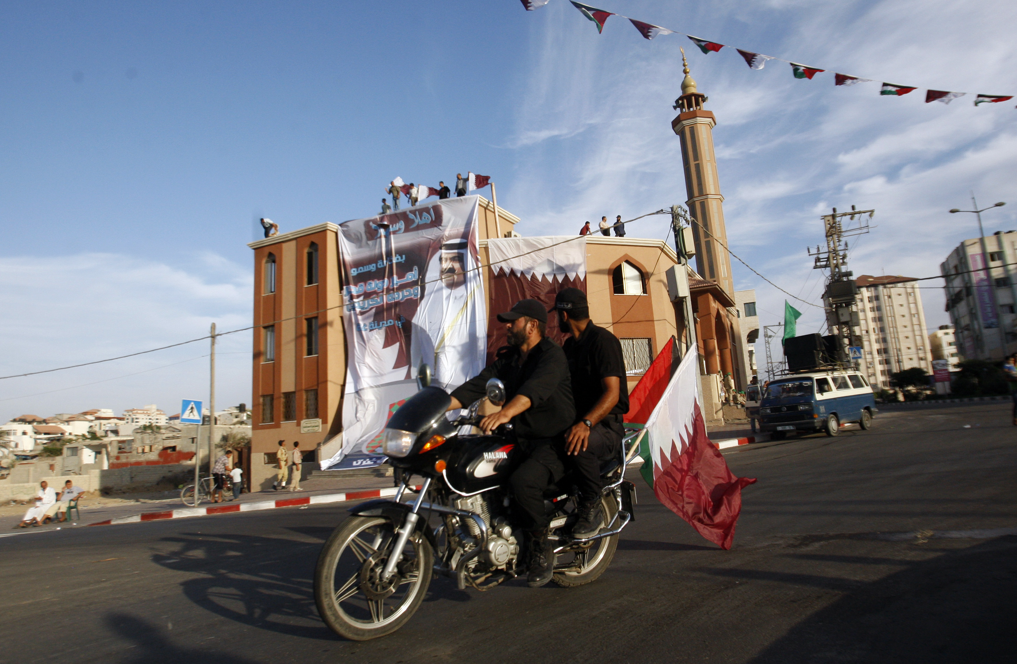 Palestinian security ride a motorcycle in front of a banner with the picture of Emir of Qatar Sheikh Hamad bin Khalifa al-Thani, on a mosque in Gaza City Tuesday, Oct. 23, 2012. The emir of Qatar received a hero's welcome in Gaza on Tuesday, becoming the first head of state to visit the Palestinian territory since the Islamist militant Hamas seized control there in 2007. (AP Photo/Hatem Moussa)