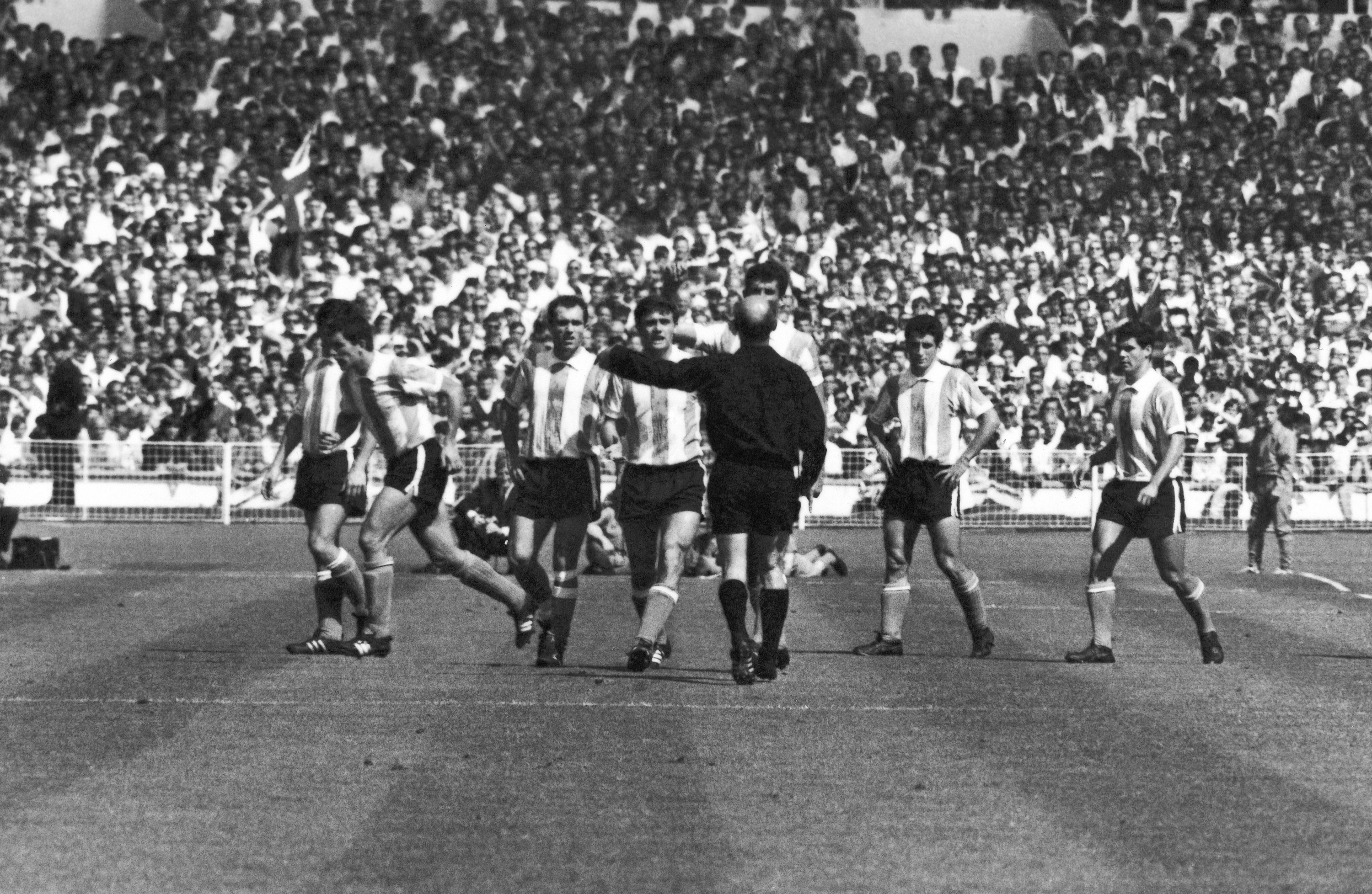West German referee Rudolf Kreitlein tries to pacify angry Argentinian players after sending off teammate Antonio Rattin during the 1966 World Cup quarterfinal