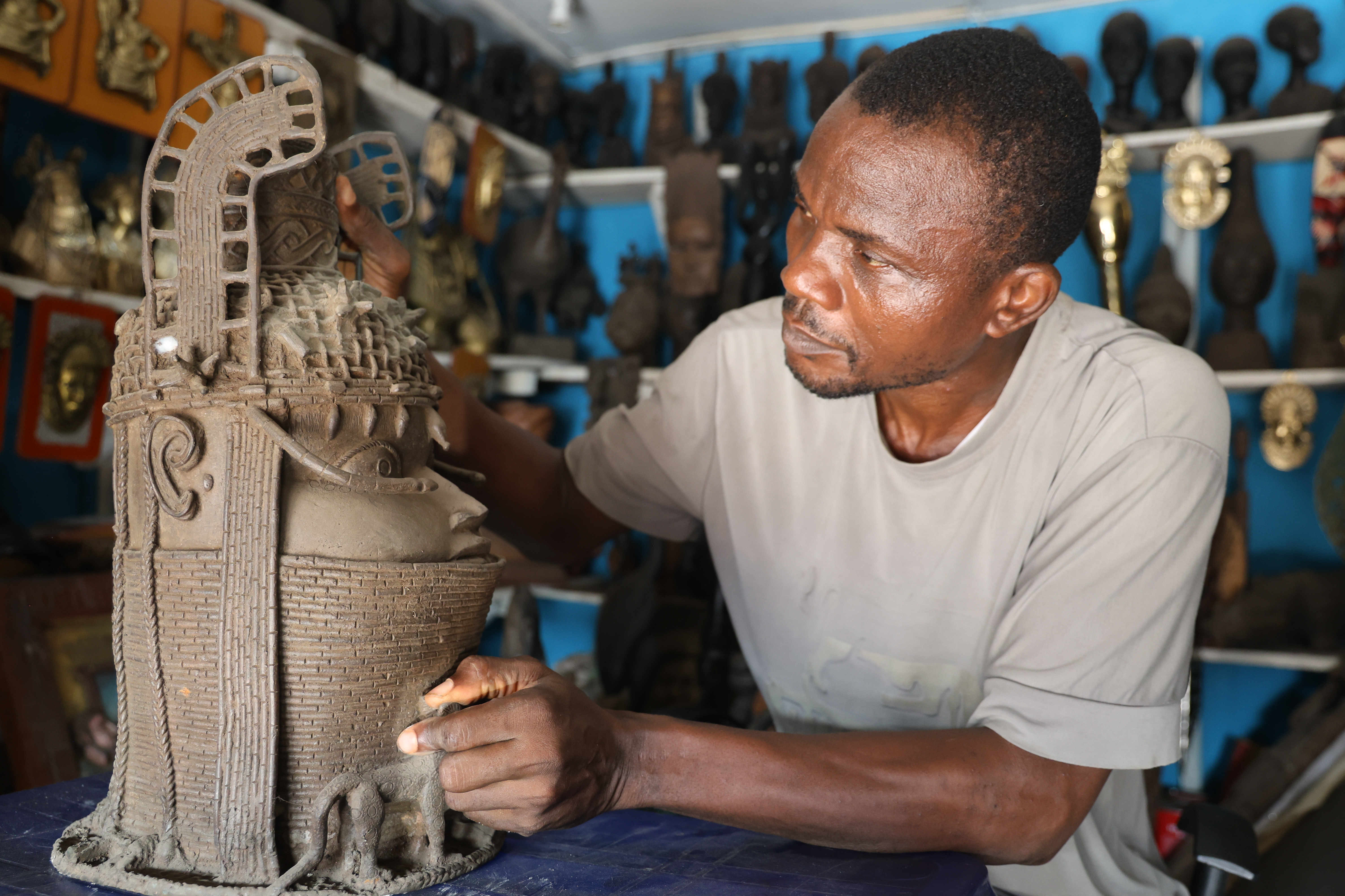 Agbonmwenre Alex gives shape to a bronze sculpture, drawing on skills he has practised since childhood