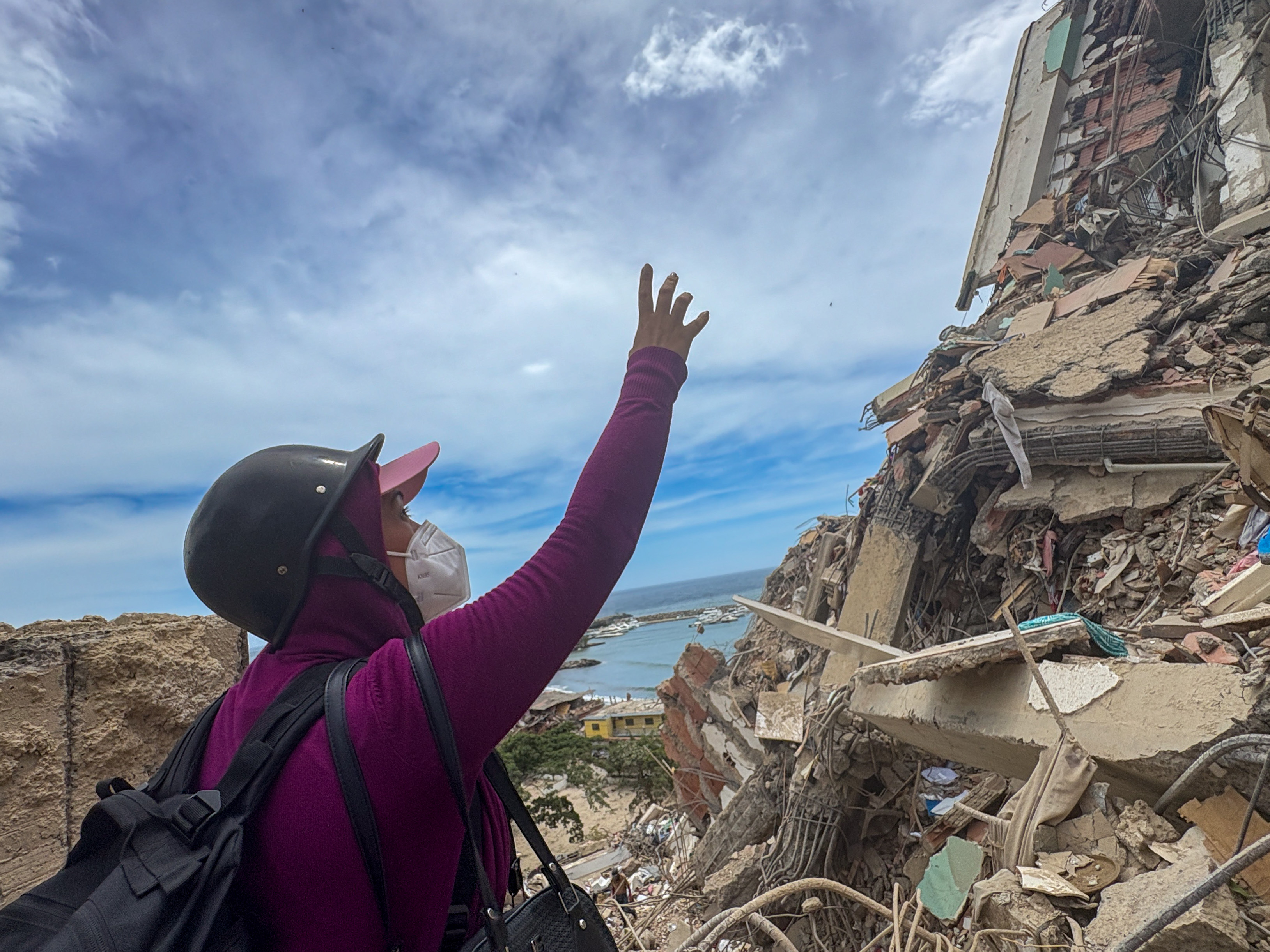Andreina Velasquez points to a fallen building
