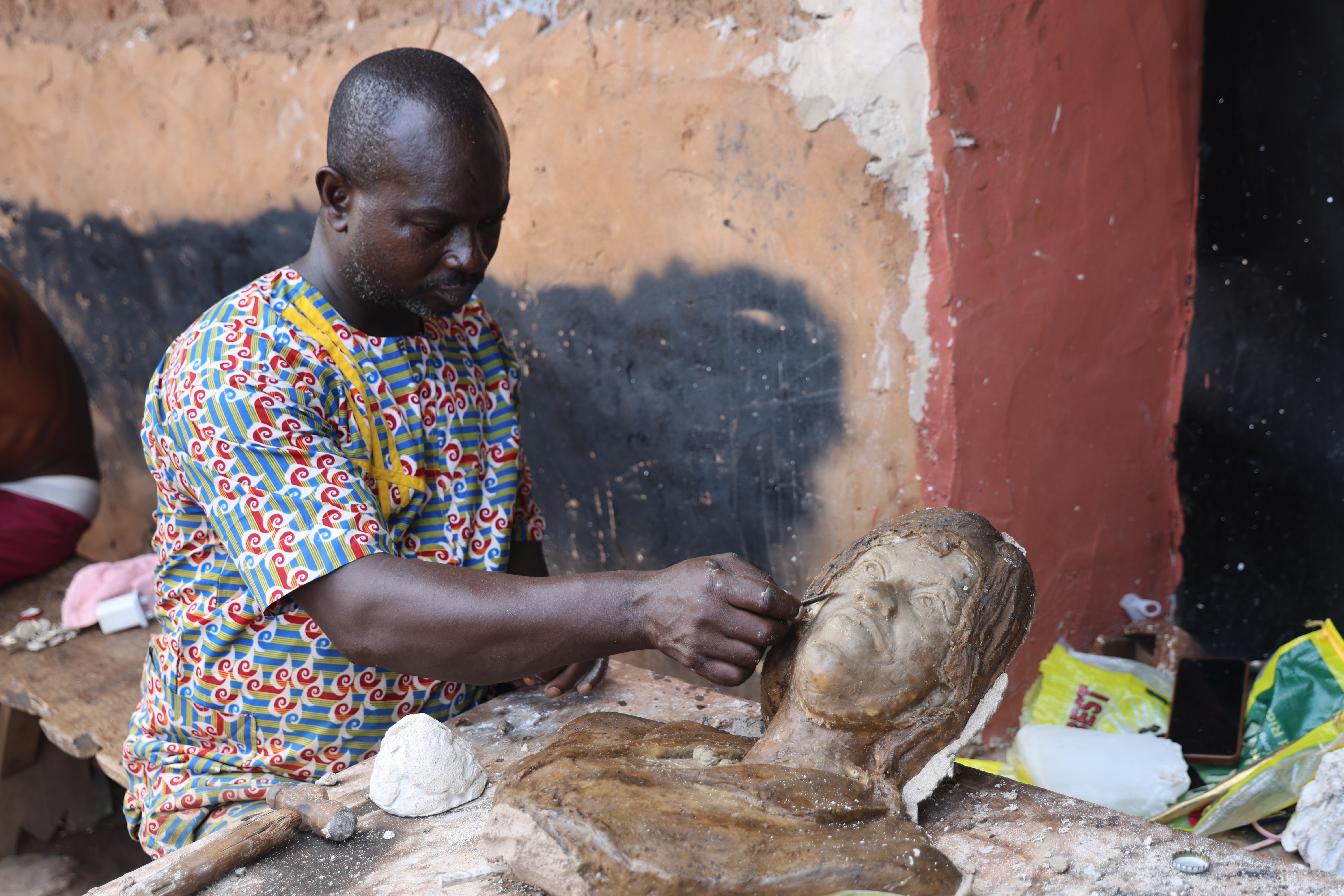 Double Chief refines a bronze sculpture in his workshop on Igun Street