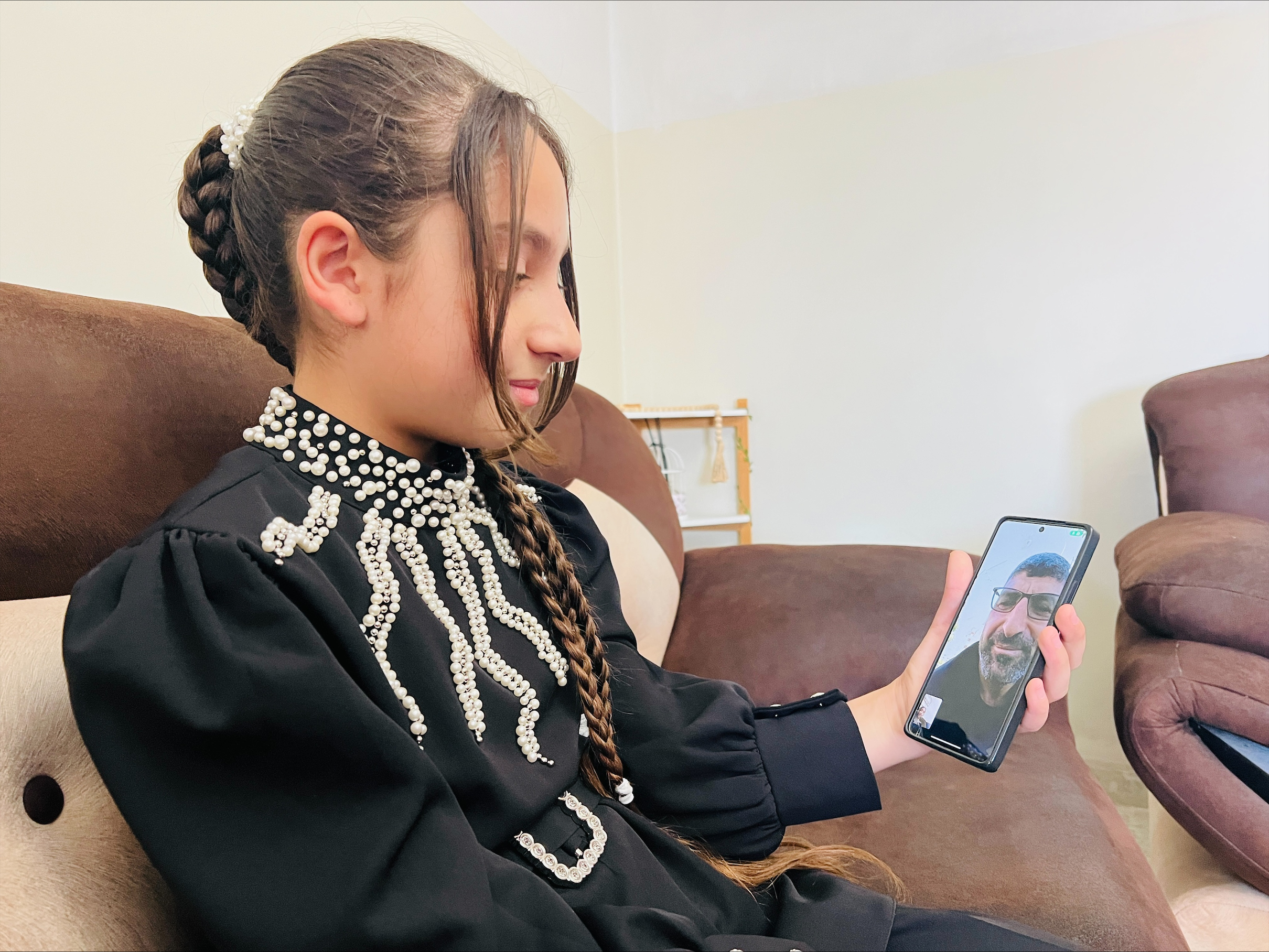 Bushra is holding her father's photo hoping to meet him soon [Fayha Shalash/Al Jazeera]