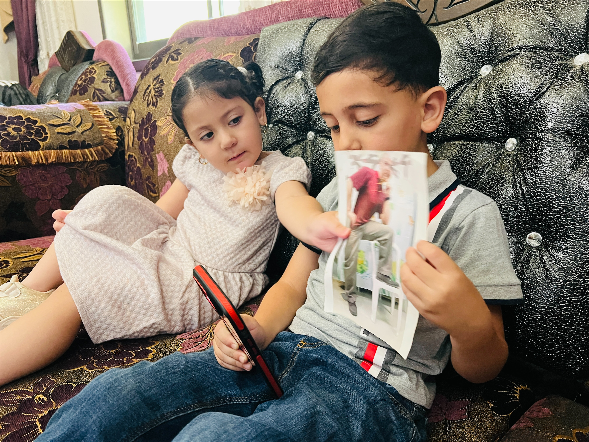 Akram and Julia talk to their father over the phone after being banned from traveling to meet him [Mohamad Turkman/Al Jazeera]