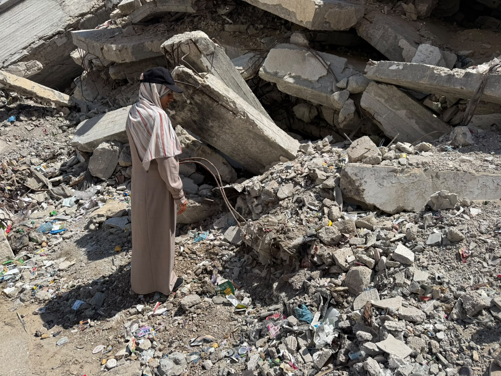 Fidaa Haji inspects the ruins of her home, where the bodies of members of her family remain trapped under the rubble in Gaza City. [Lina Abuzayed/Al Jazeera]