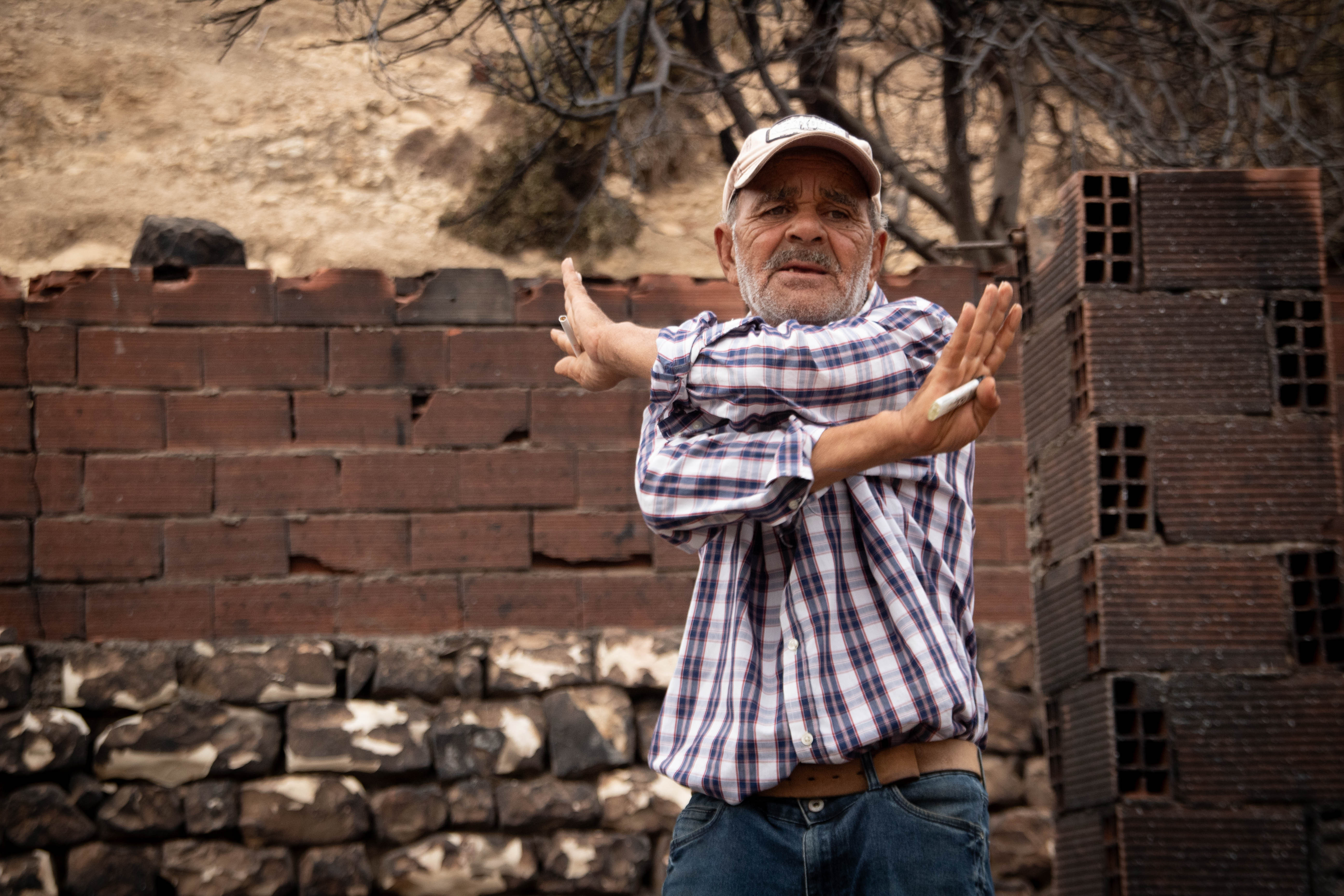 Farmer Mongi Abdeli stands among the burnt remains of his farm in Kef governorate, Tunisia