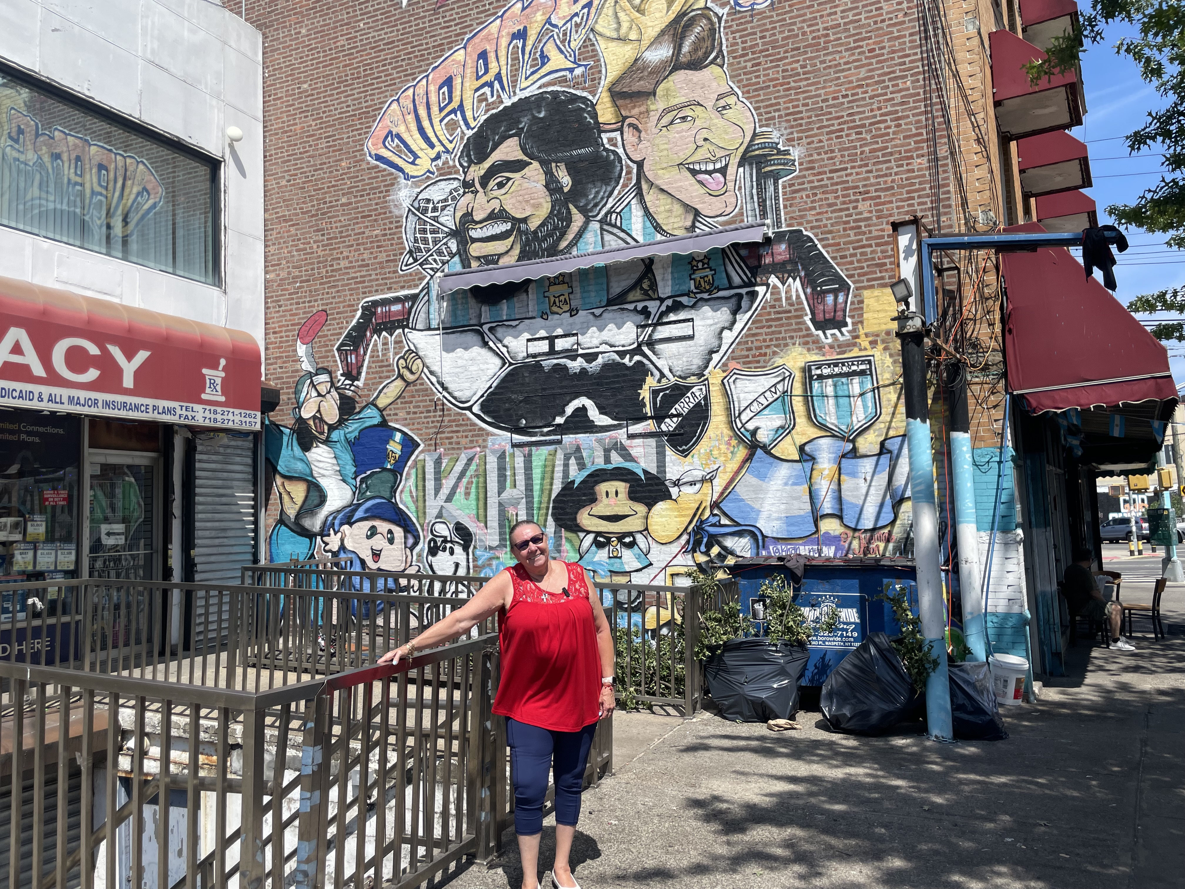 A woman stands in front of a Maradona-Messi mural.