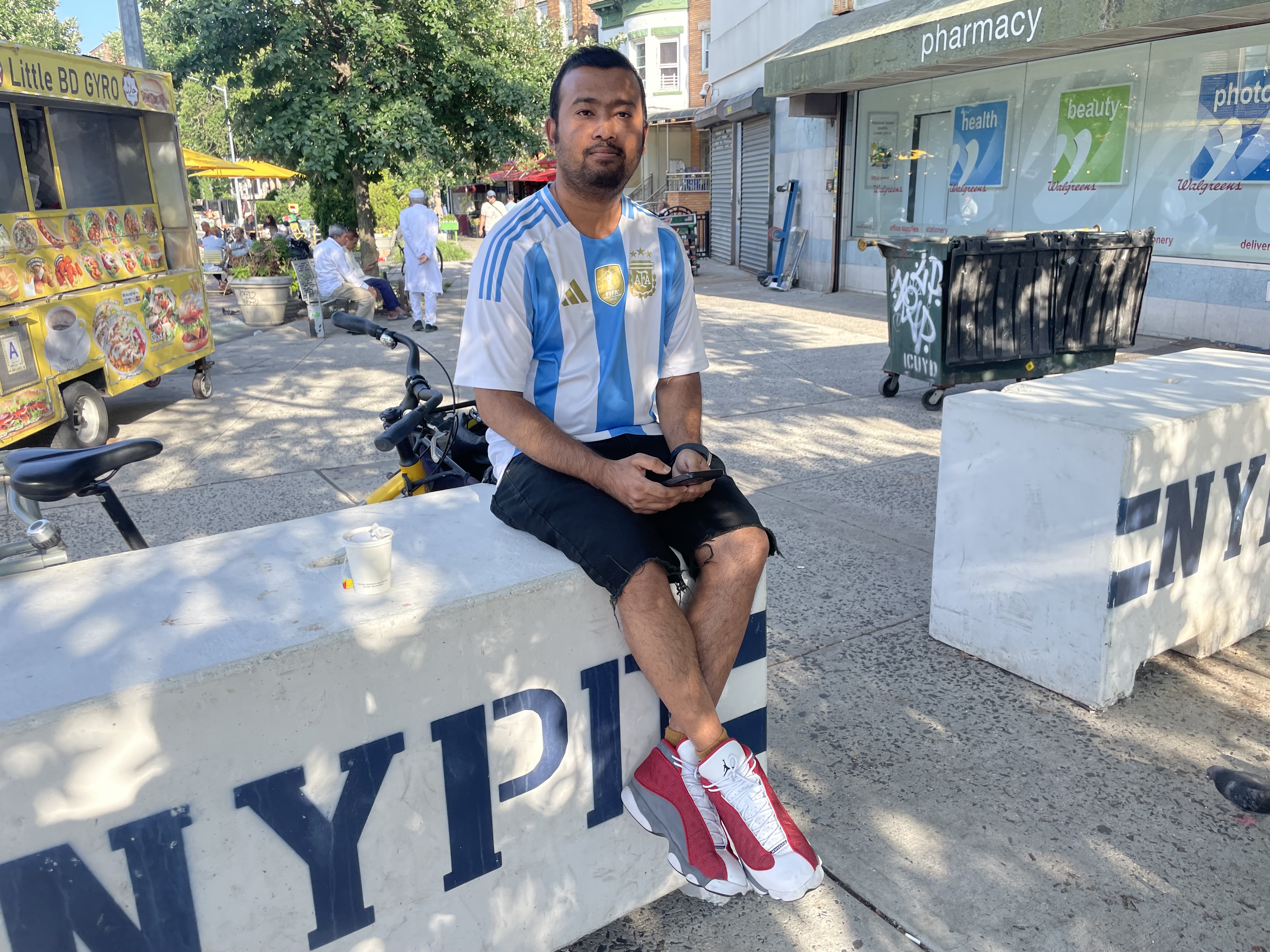 Argentina fan Sajid Bhuyan sits on an NYPD barrier in Kensington