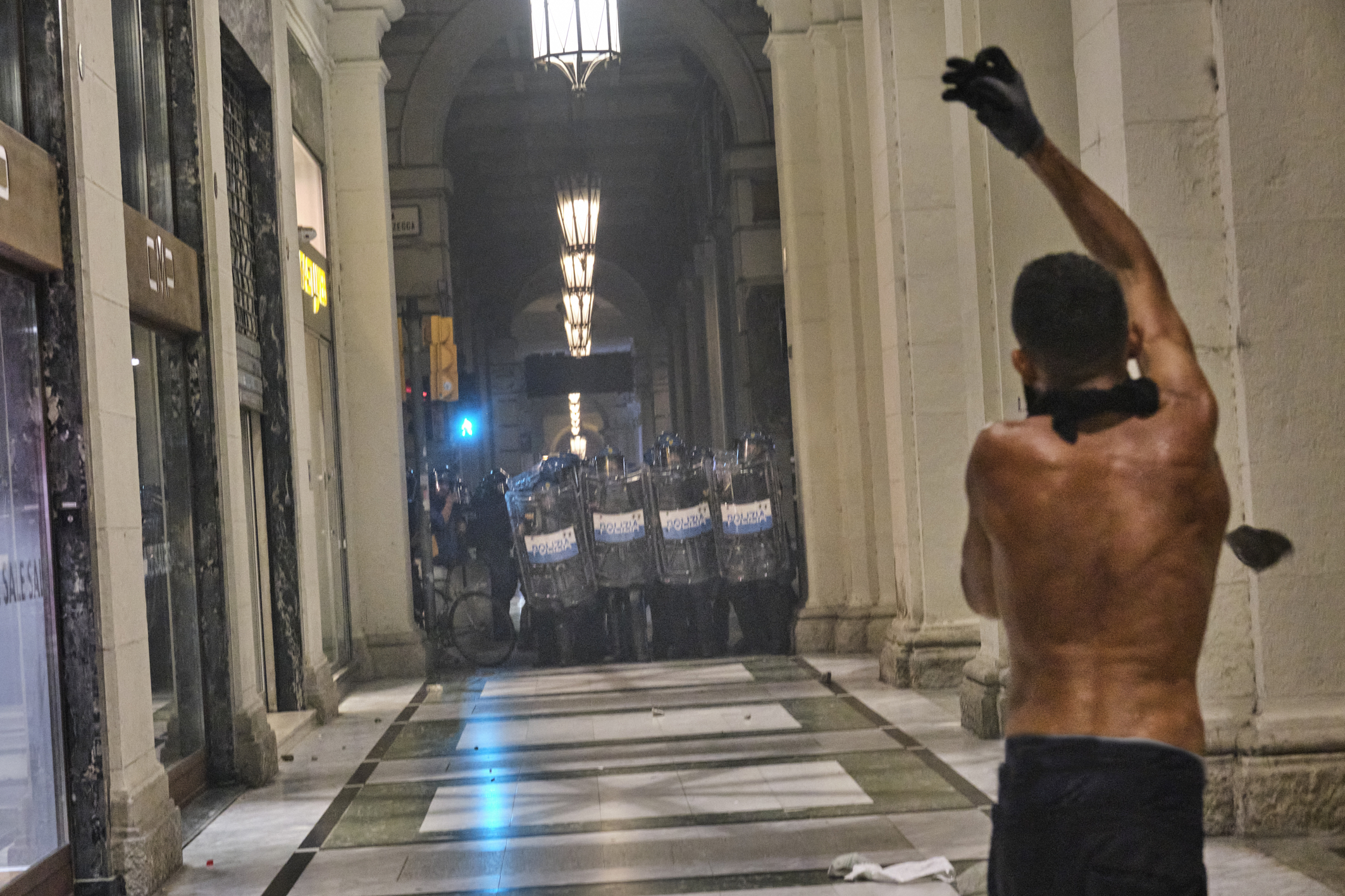 A protester gestures with a raised hand as police officers stand nearby during a demonstration in Bologna following Fakir’s death [Dea Sibilla/Al Jazeera]