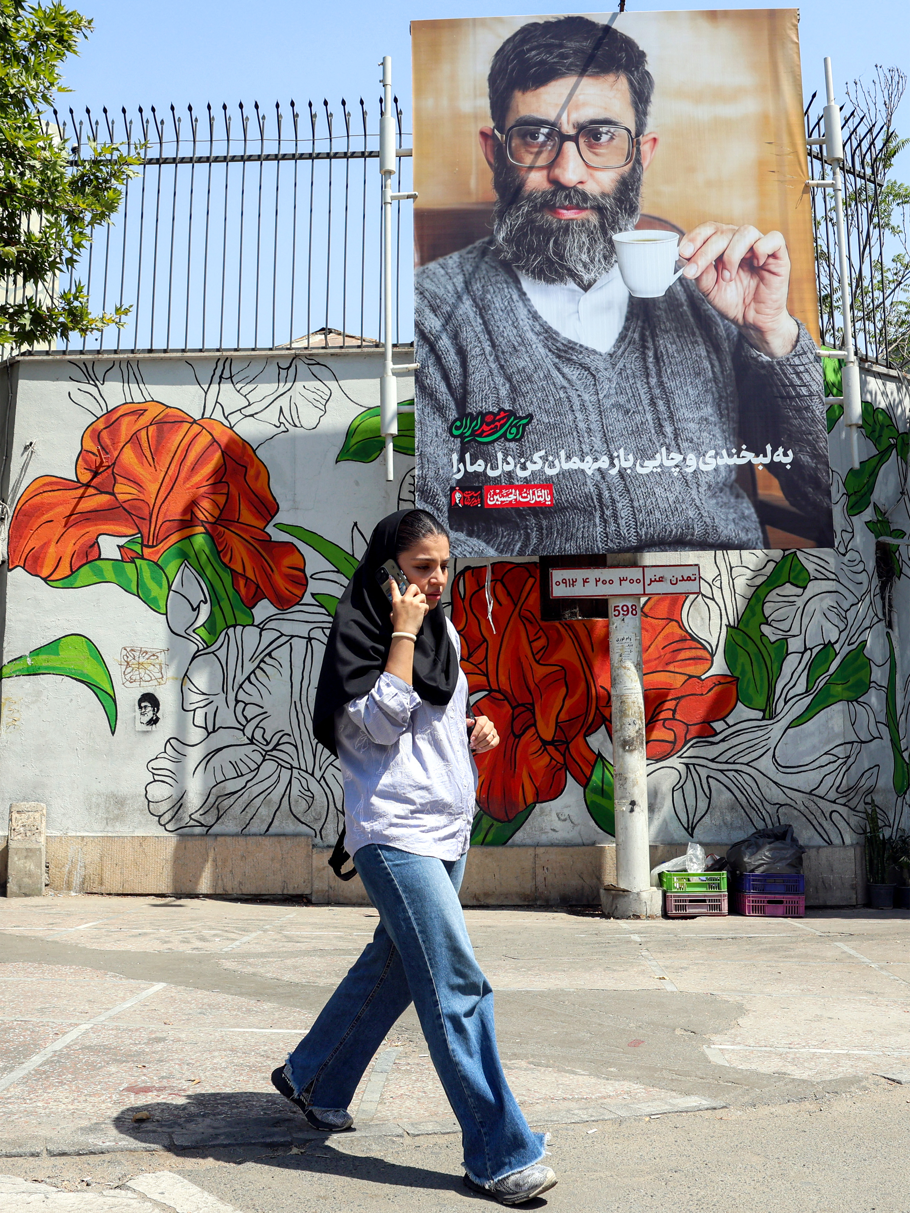 A woman walks past a billboard in Tehran