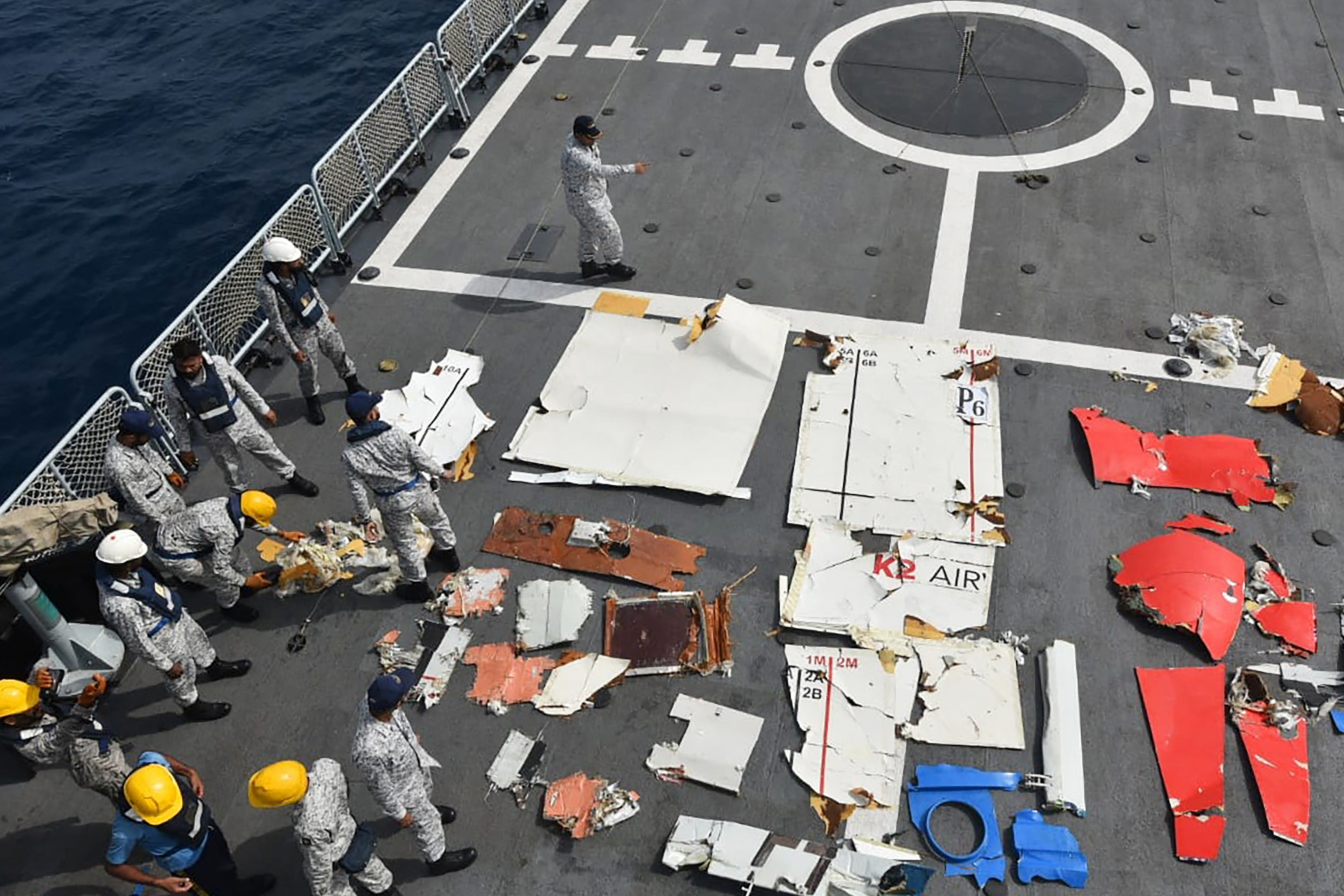 This handout photograph taken on July 8, 2026 and released by the Pakistan Airports Authority shows Pakistan Navy and Pakistan Maritime Security Agency personnel standing next to the wreckage of the K2 Airways Cargo Boeing 737, after it was recovered during a search and rescue operation in the Arabian Sea, off Ormara town.