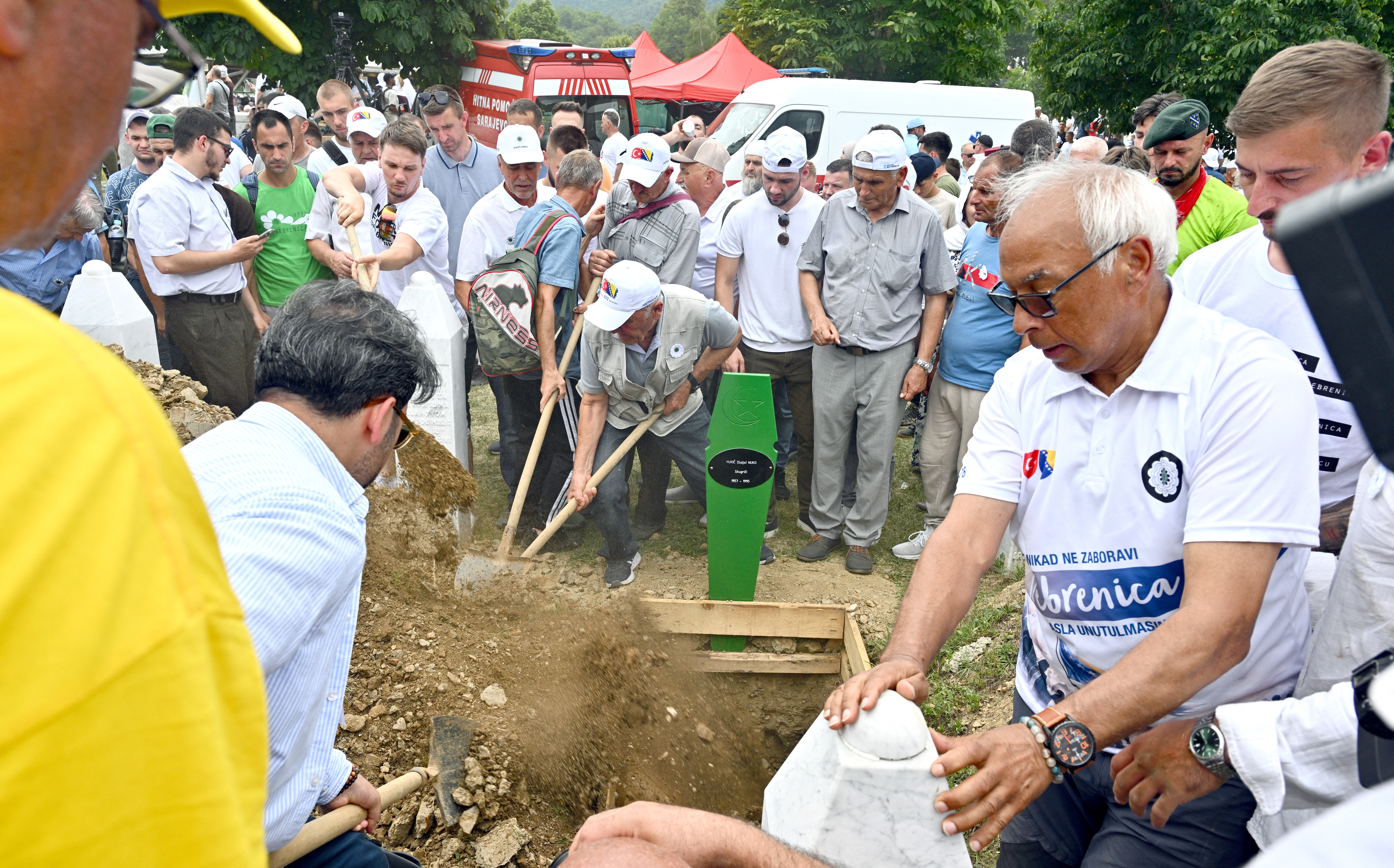 Bosnian Muslims bury a casket containing the remains of victims of the 1995 Srebrenica massacre at the memorial cemetery in the village of Potocari, near the eastern Bosnia town of Srebrenica