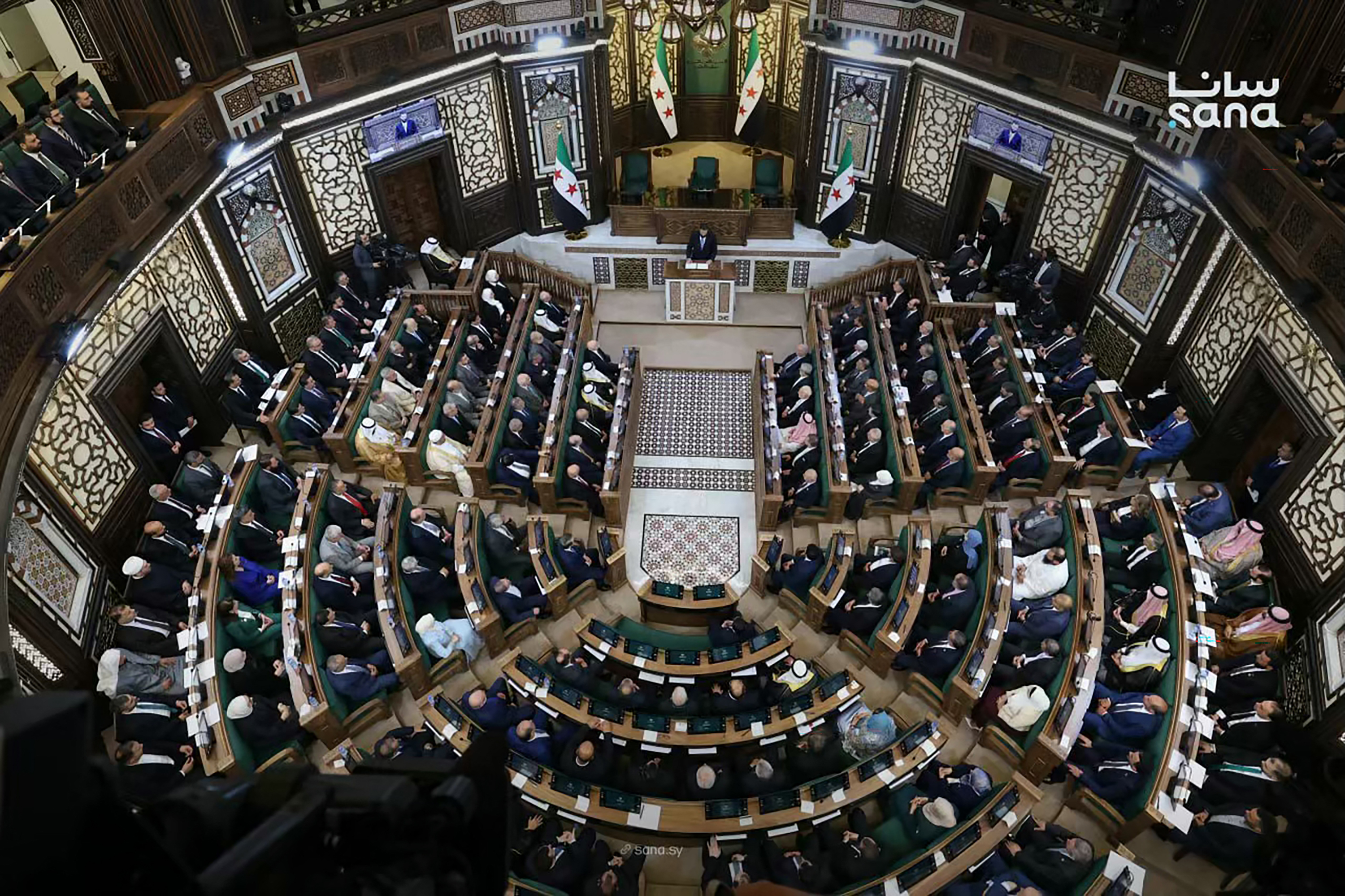 Syria's President Ahmed al-Sharaa (top, C) speaking during the first meeting of Syria's new transitional parliament in Damascus