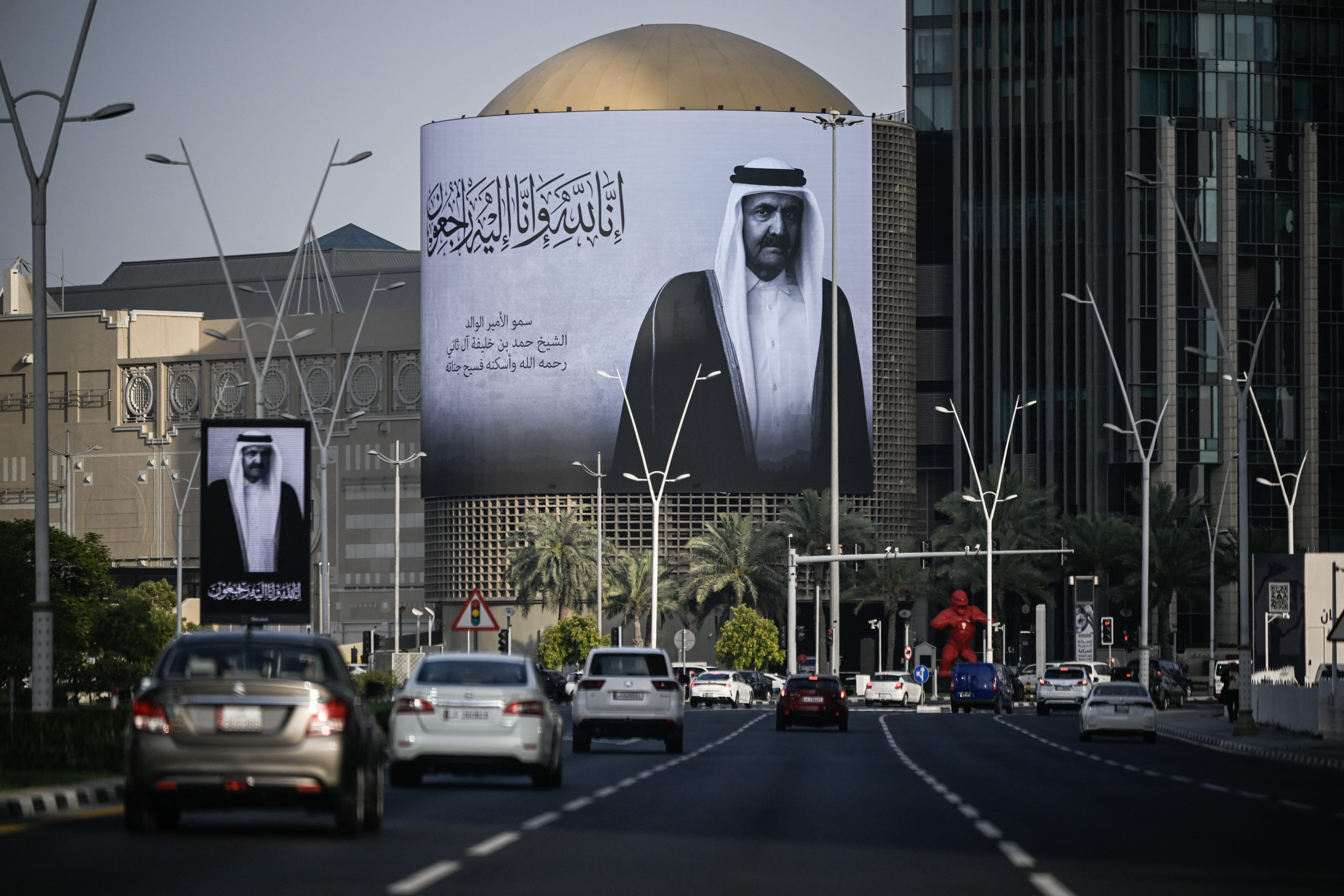 Commuters drive past a billboard bearing a portrait of Qatar’s former leader Sheikh Hamad bin Khalifa Al Thani in Doha on July 12, 2026, after the announcement of his death [AFP]