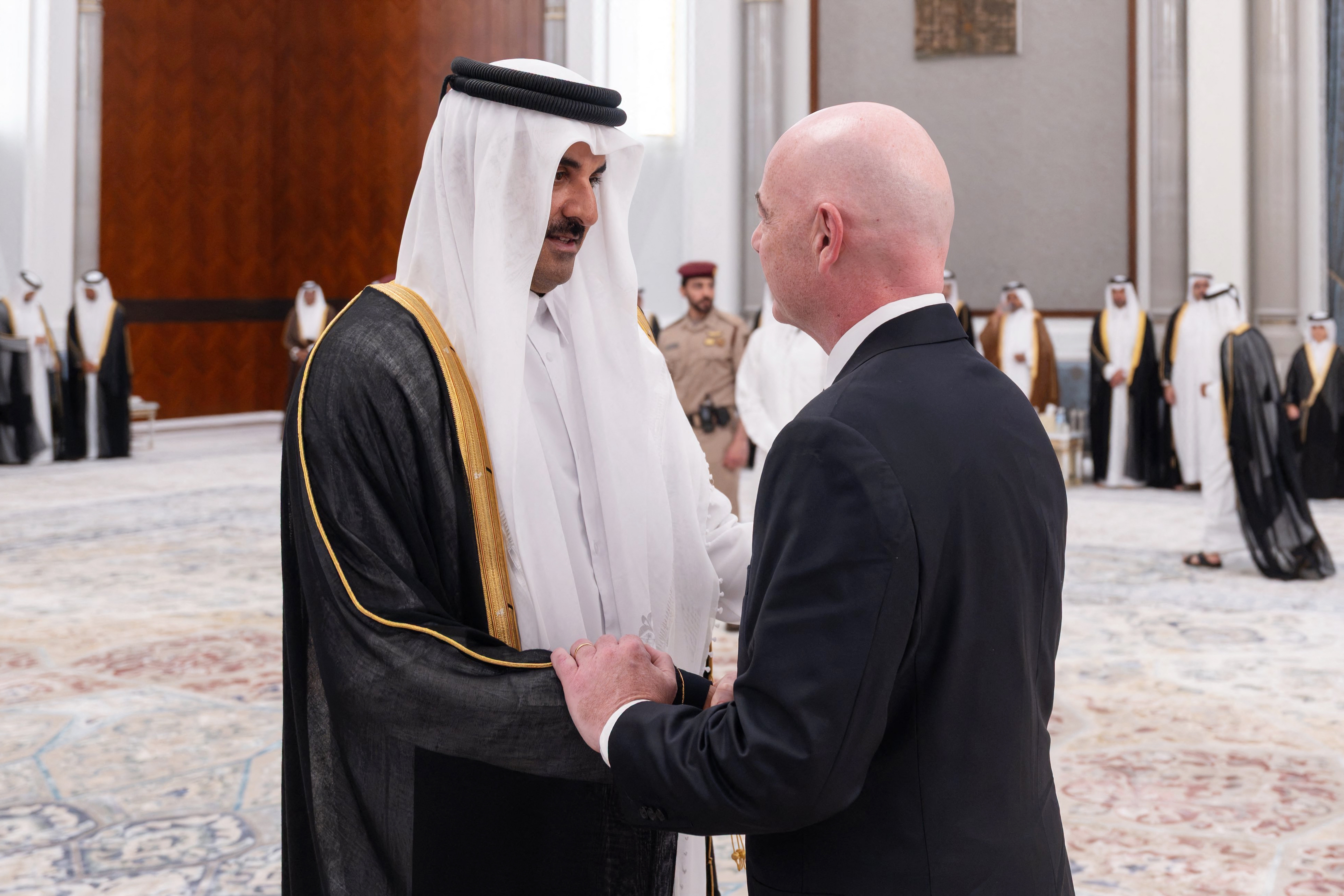 This handout photograph taken and released by Qatar's Amiri Diwan on July 13, 2026 shows Qatar's Emir Sheikh Tamim bin Hamad Al Thani (L) receiving condolences from FIFA President Gianni Infantino, following the death of his father, former leader Sheikh Hamad bin Khalifa Al Thani, at the Lusail Palace on the outskirts of Doha.