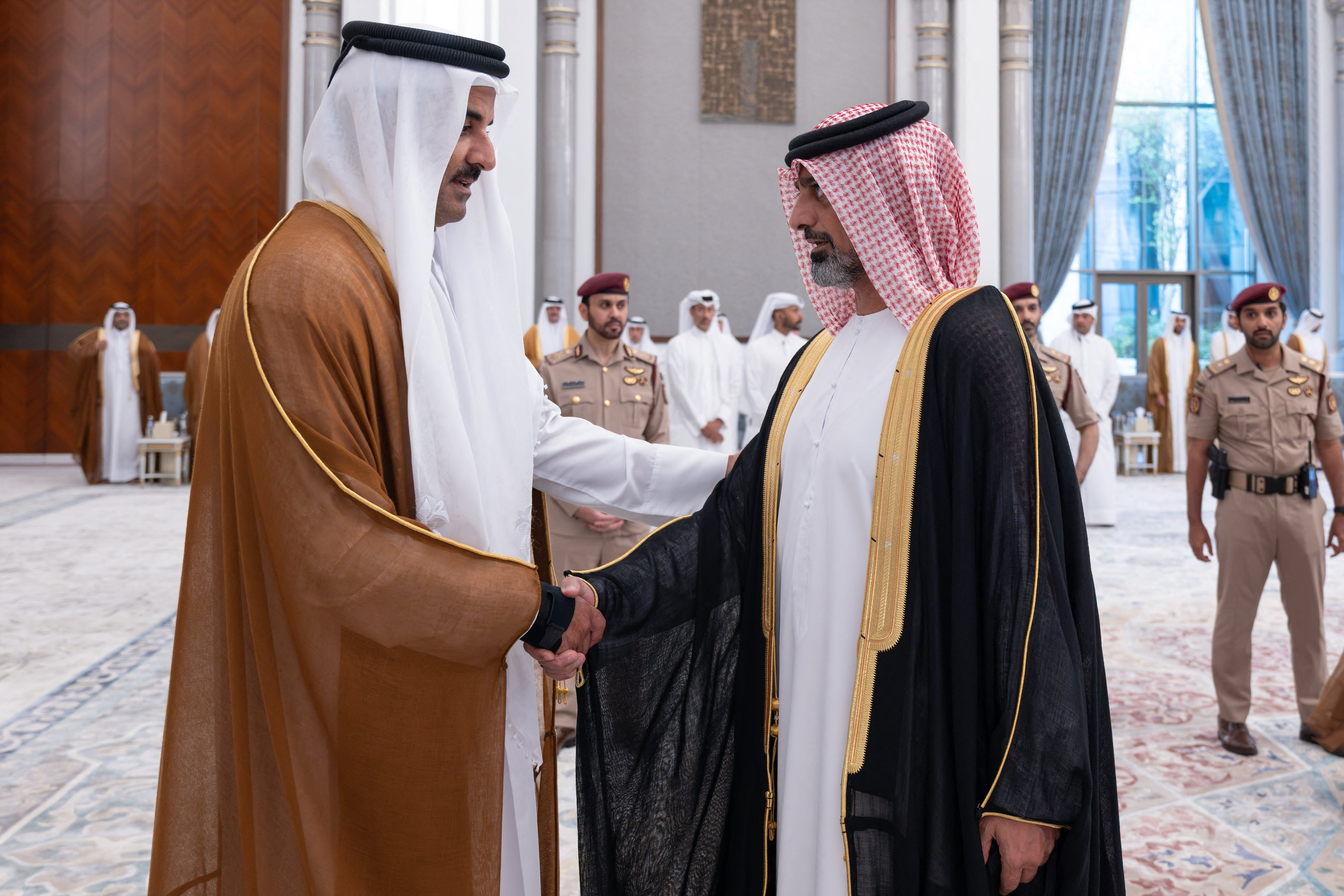 This handout photograph realeased by Qatar's Amiri Diwan shows Qatar's Emir Sheikh Tamim bin Hamad Al Thani (L) receiving condolences from Sheikh Ammar bin Humaid Al Nuaimi, Crown Prince and Chairman of the Executive Council of the Emirate of Ajman following the death of his father, former leader Sheikh Hamad bin Khalifa Al Thani, at Lusail Palace on the outskirts of doha on July 13, 2026.