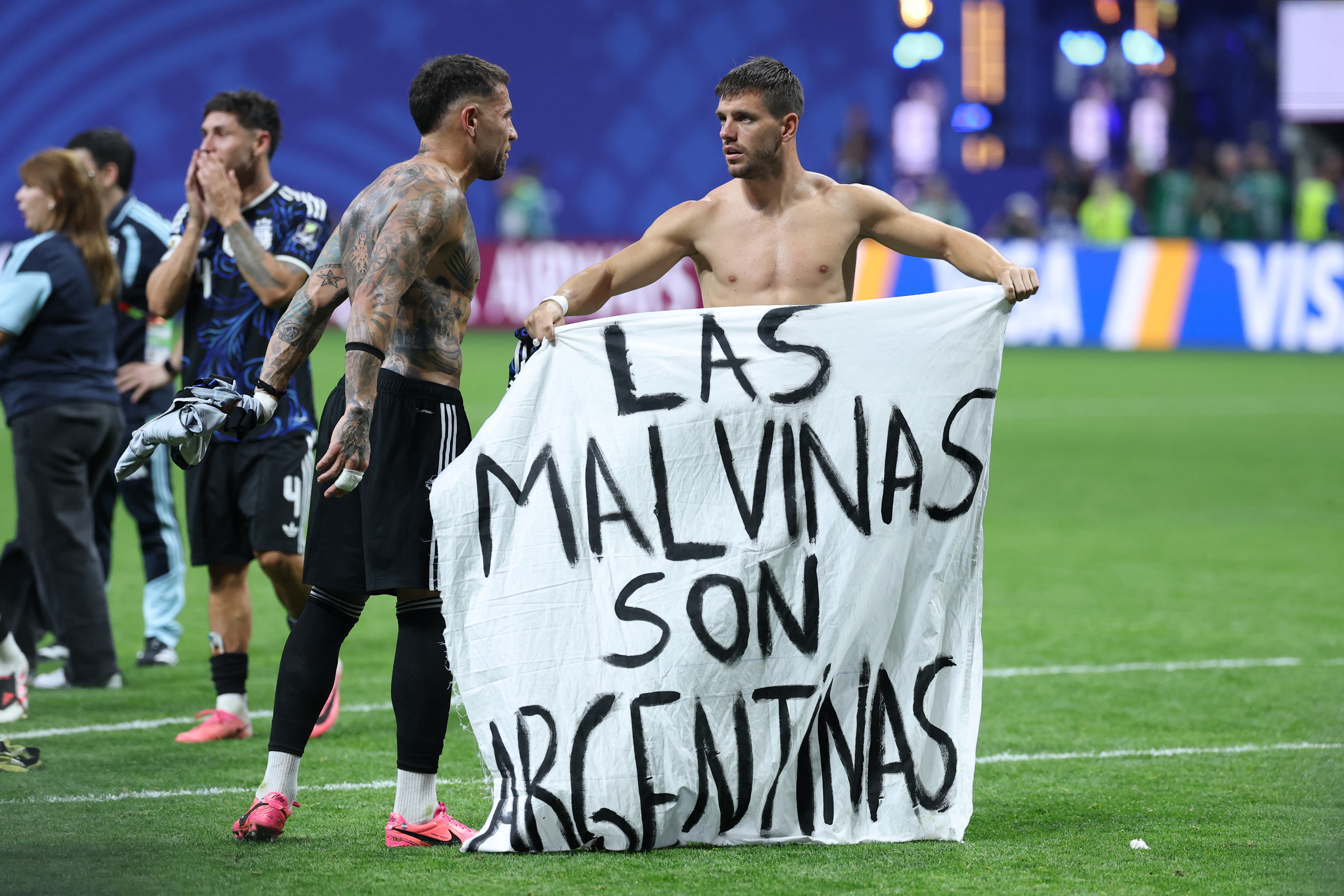 Argentina's defender #19 Nicolas Otamendi (L) and midfielder #11 Giovani Lo Celso show a banner that reads in Spanish, "The Malvinas (Falkland Islands) belong to Argentina," on the football field.
